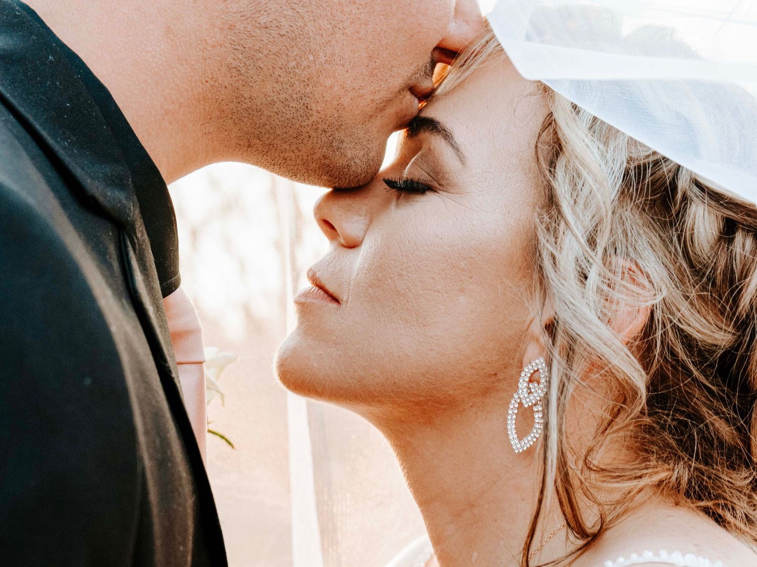 Groom about to kiss the bride's forehead in a close wedding portrait