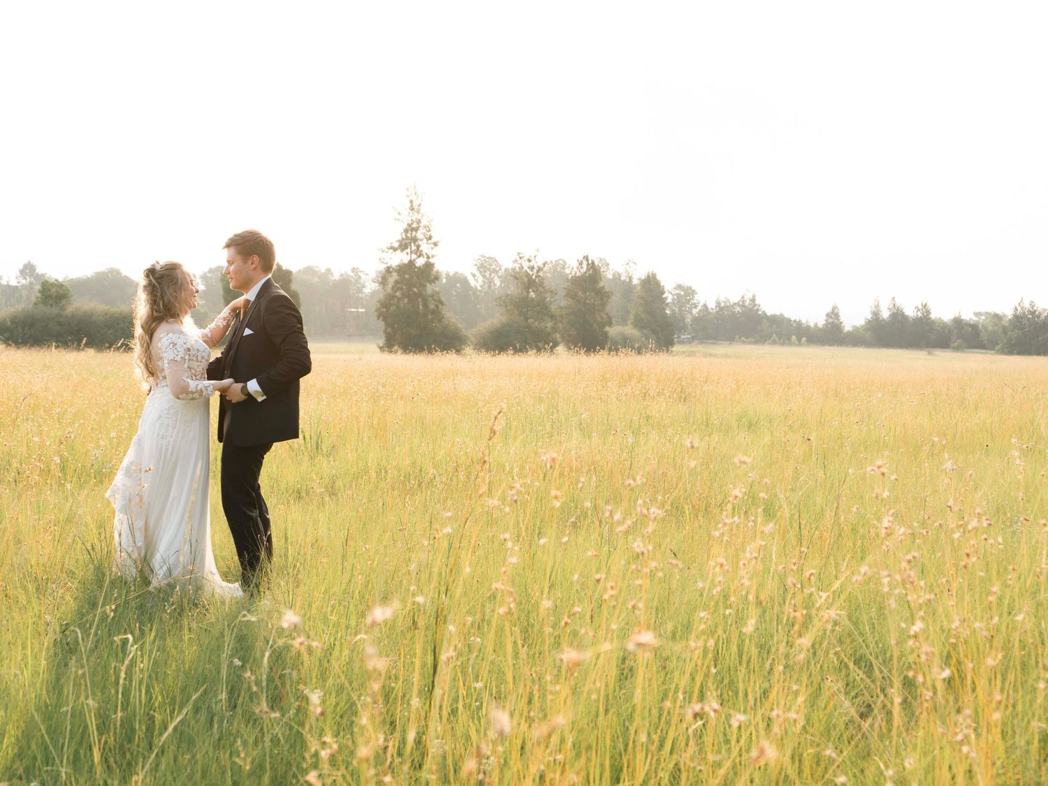 Bride and groom embracing in a field of tall grass
