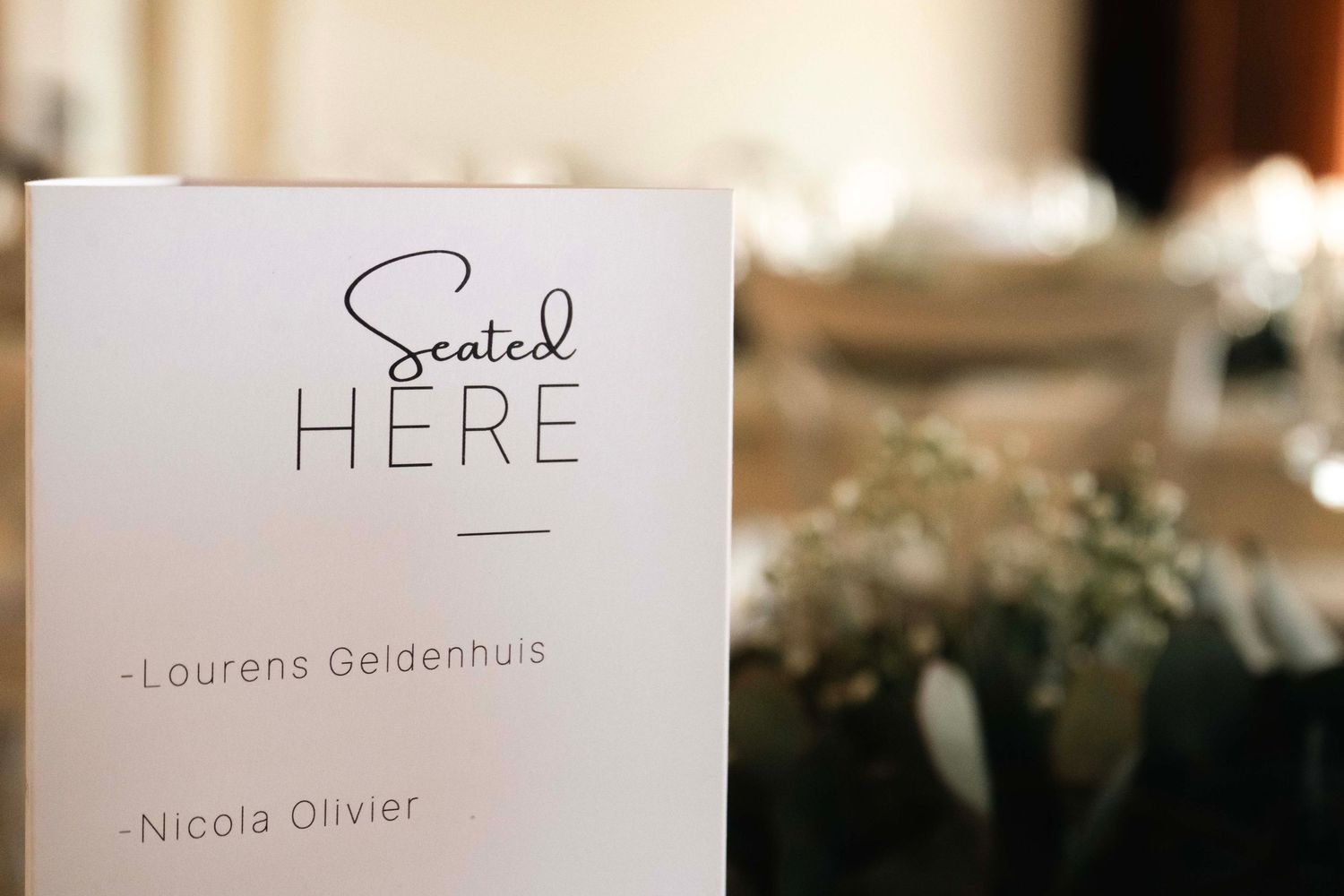 Wedding seating chart card displayed on a table with greenery