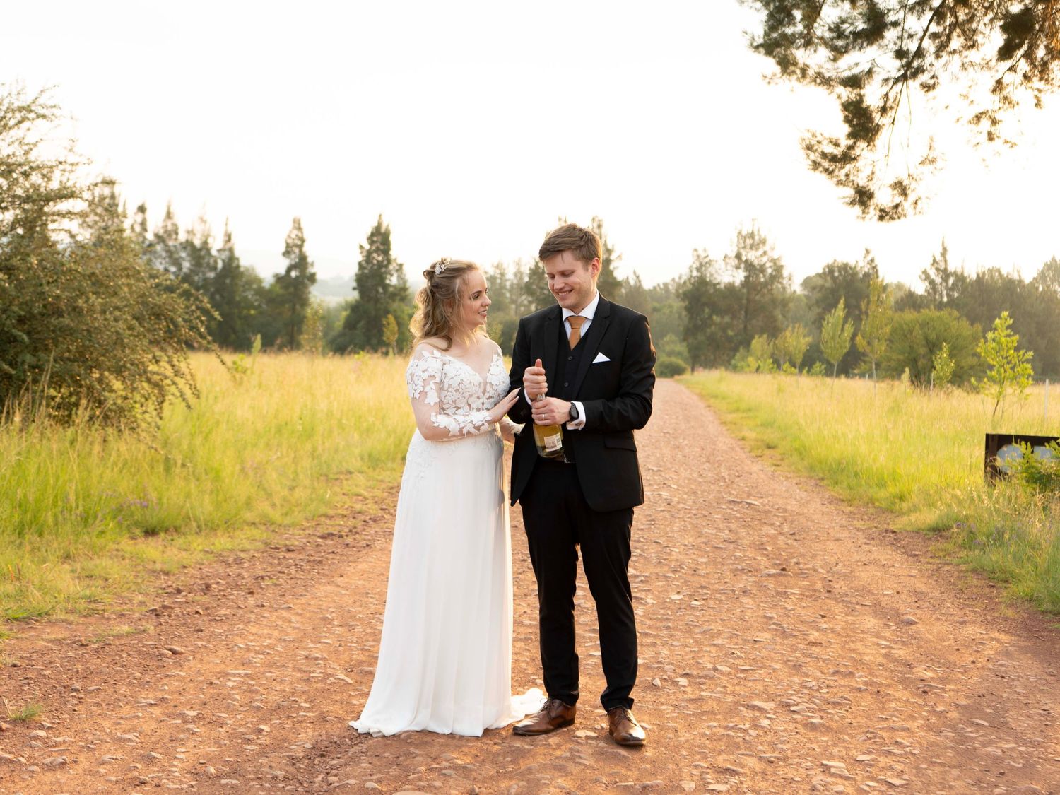 Bride and groom standing together on a rural dirt road at their wedding