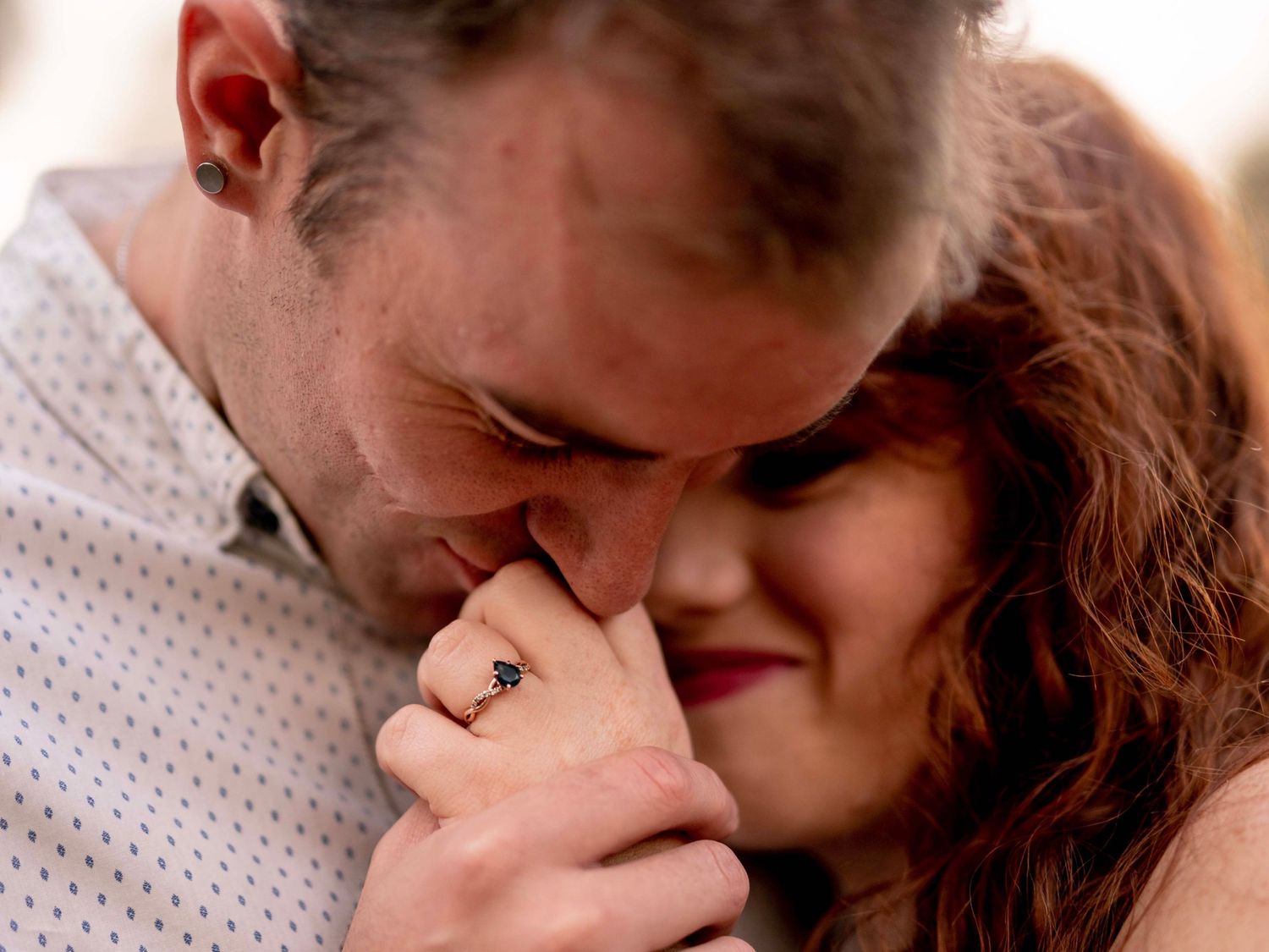 Close-up of a woman's face and hand showing her engagement ring