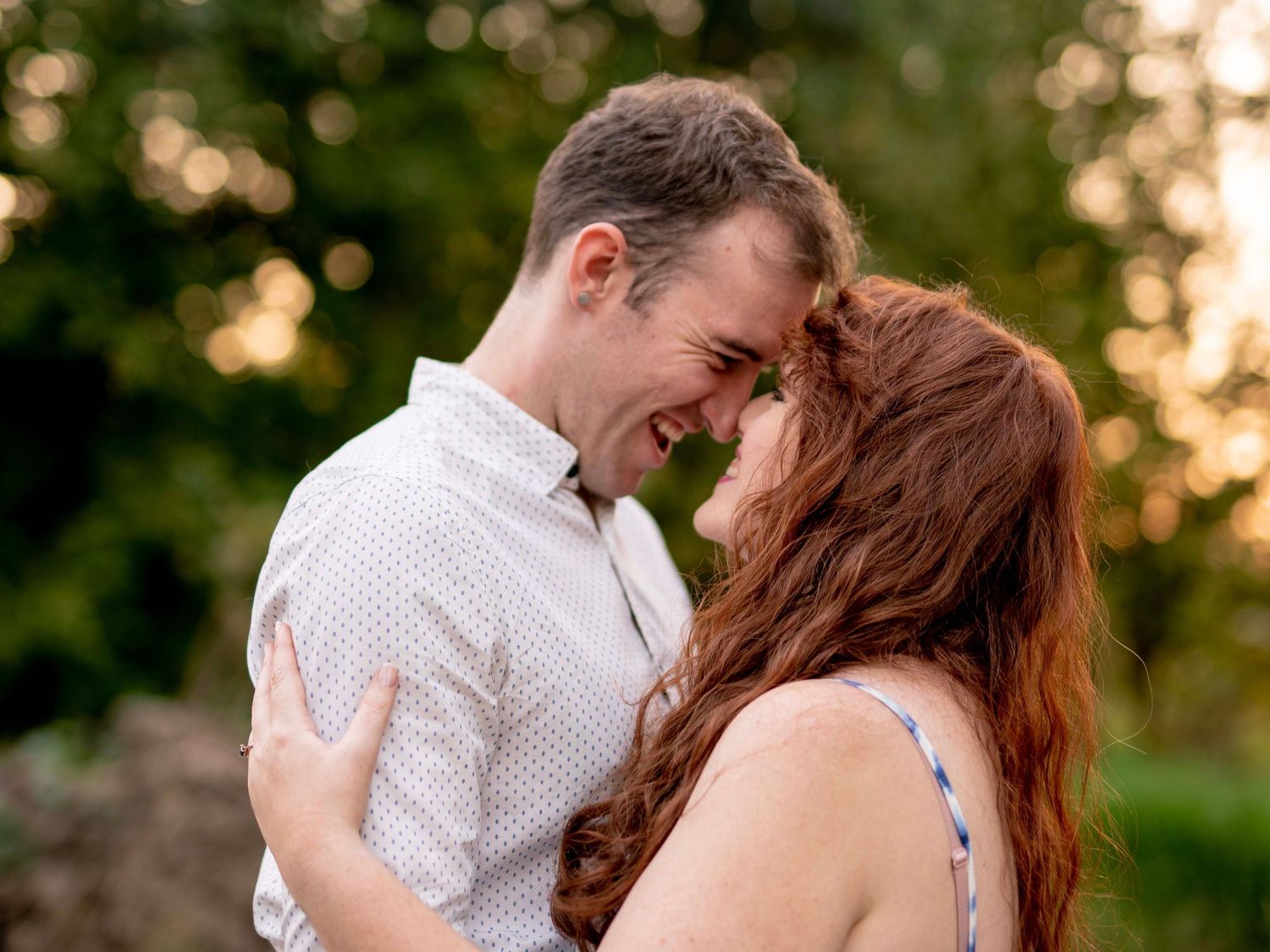 Couple embracing and smiling together at golden hour during their engagement shoot