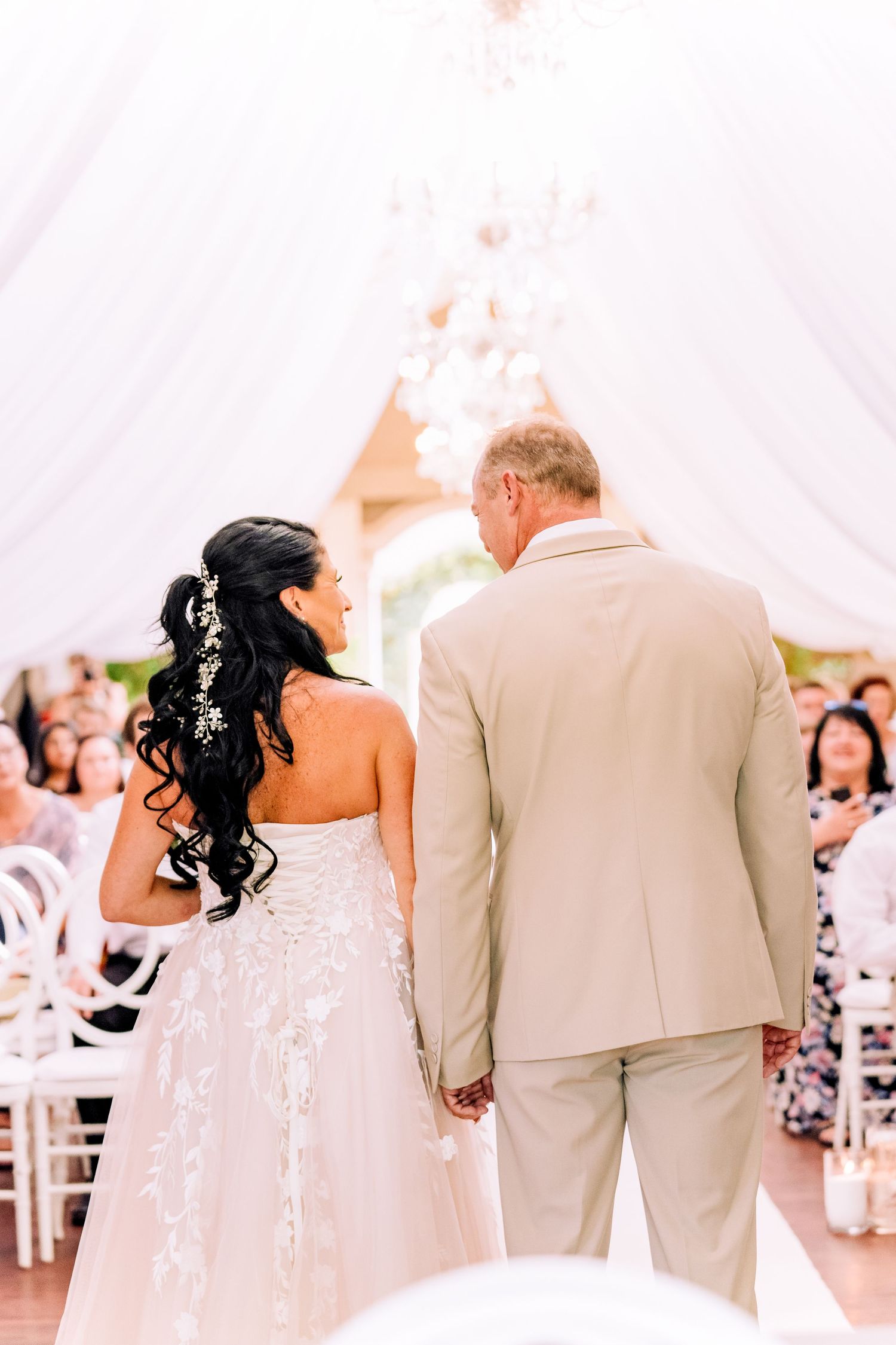 Bride walking down the aisle with her father under a draped ceremony tent
