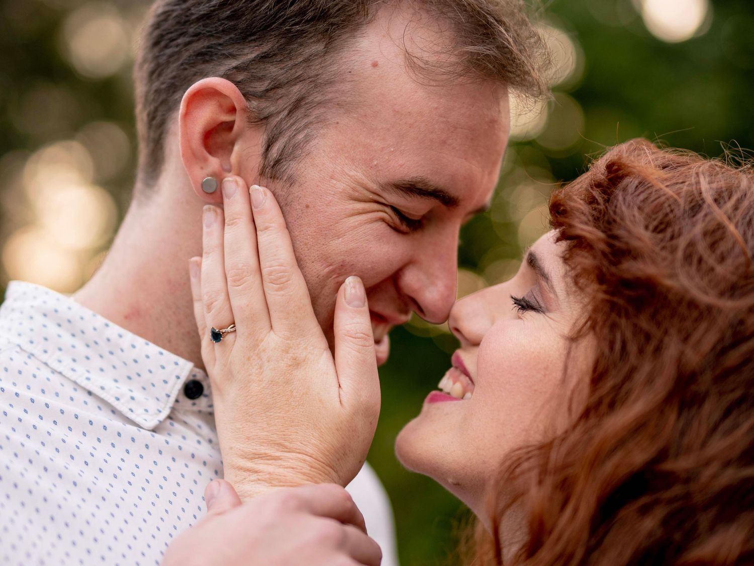 Couple smiling closely at each other outdoors during their engagement session