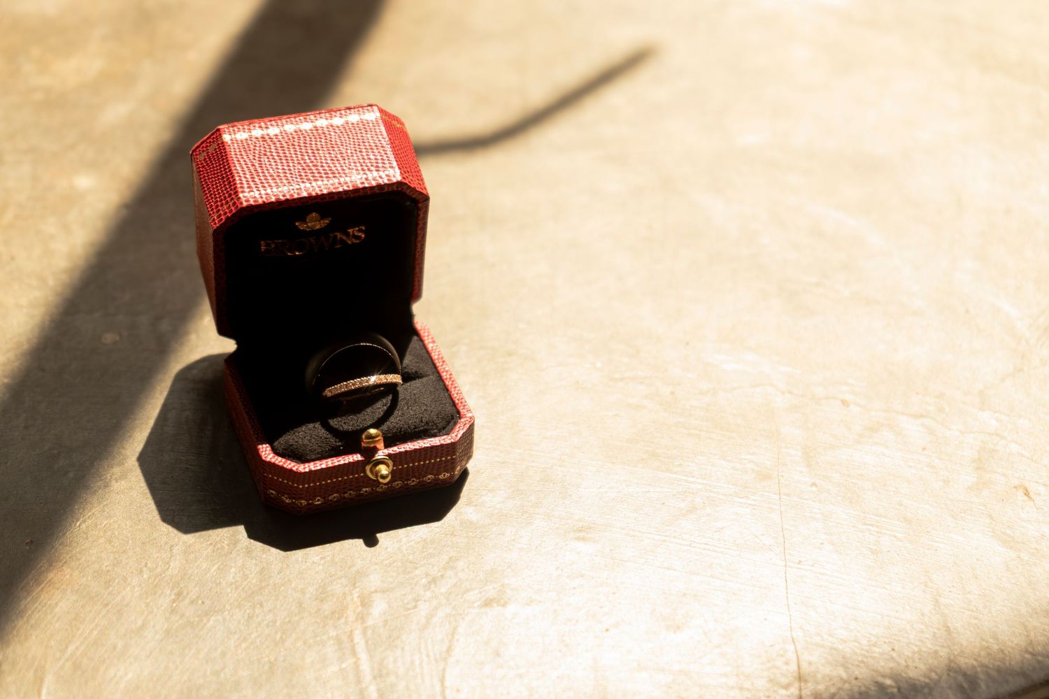 Wedding ring displayed in an open red ring box outdoors