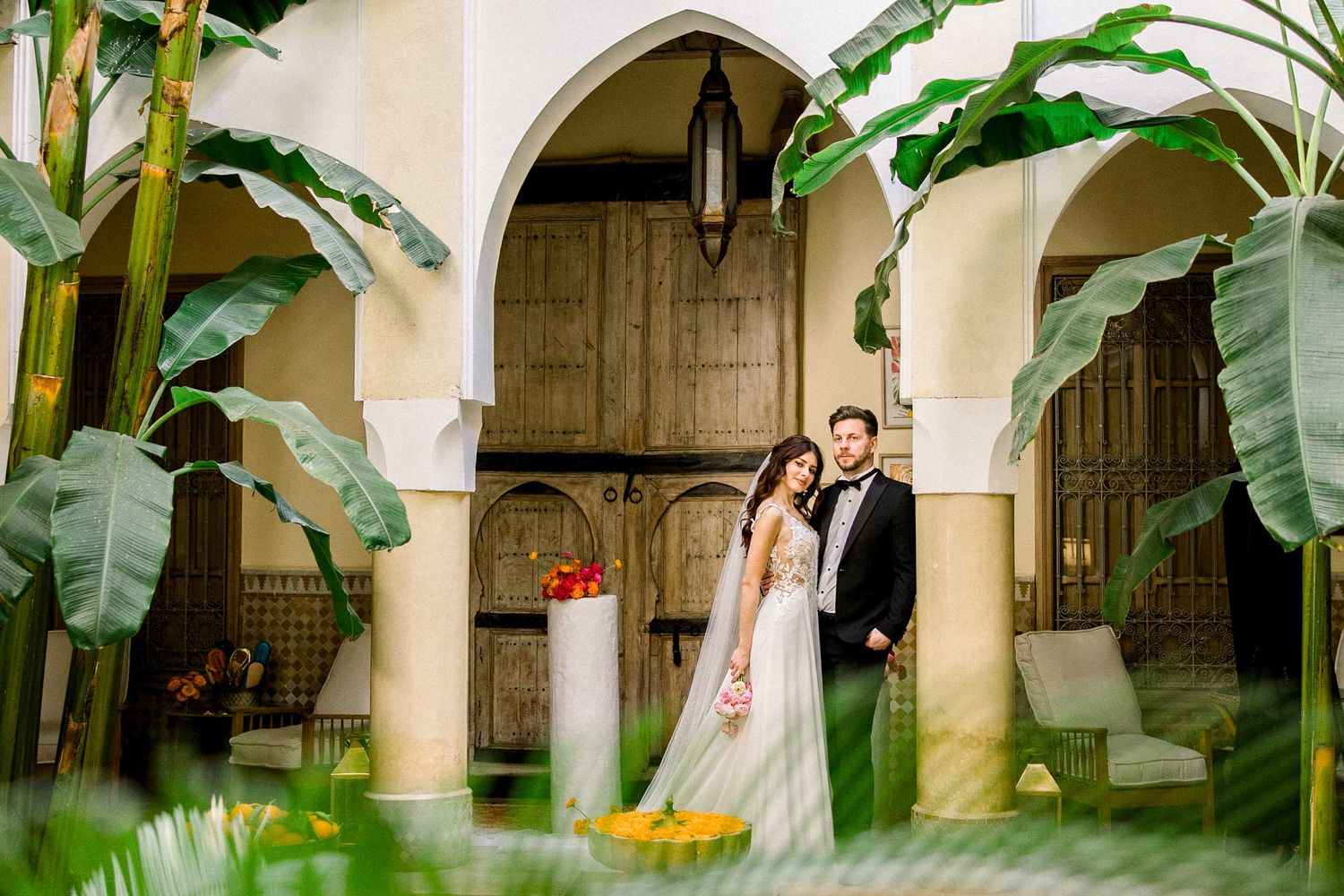 Tropical garden wedding venue with white arches and large banana leaf plants.