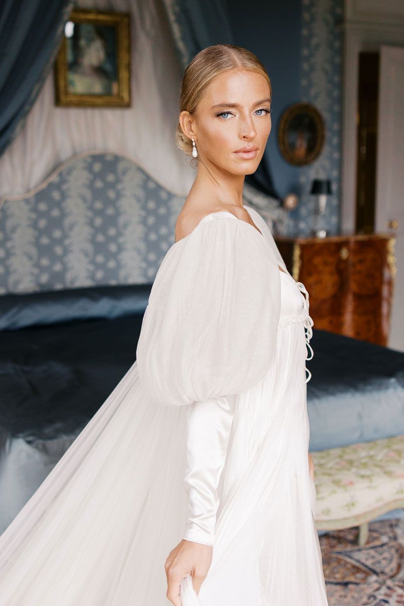 Flowing white wedding veil and dress details captured in an elegant blue room.