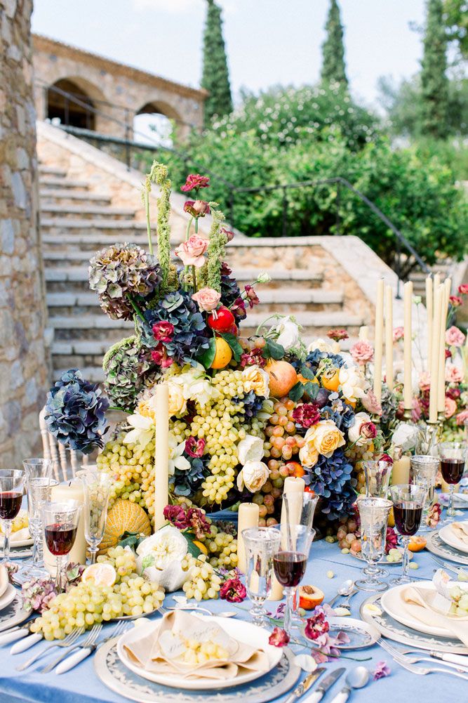 Mediterranean-style wedding table with fresh fruits, flowers, and tall white candles.