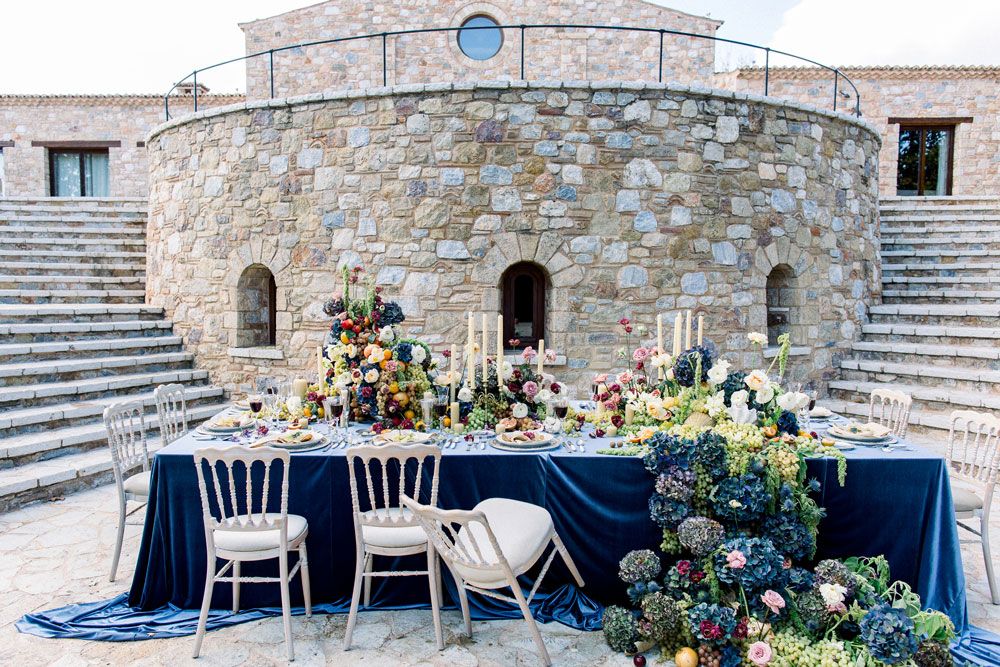 Elegant outdoor wedding reception setup with stone architecture and floral decorations.