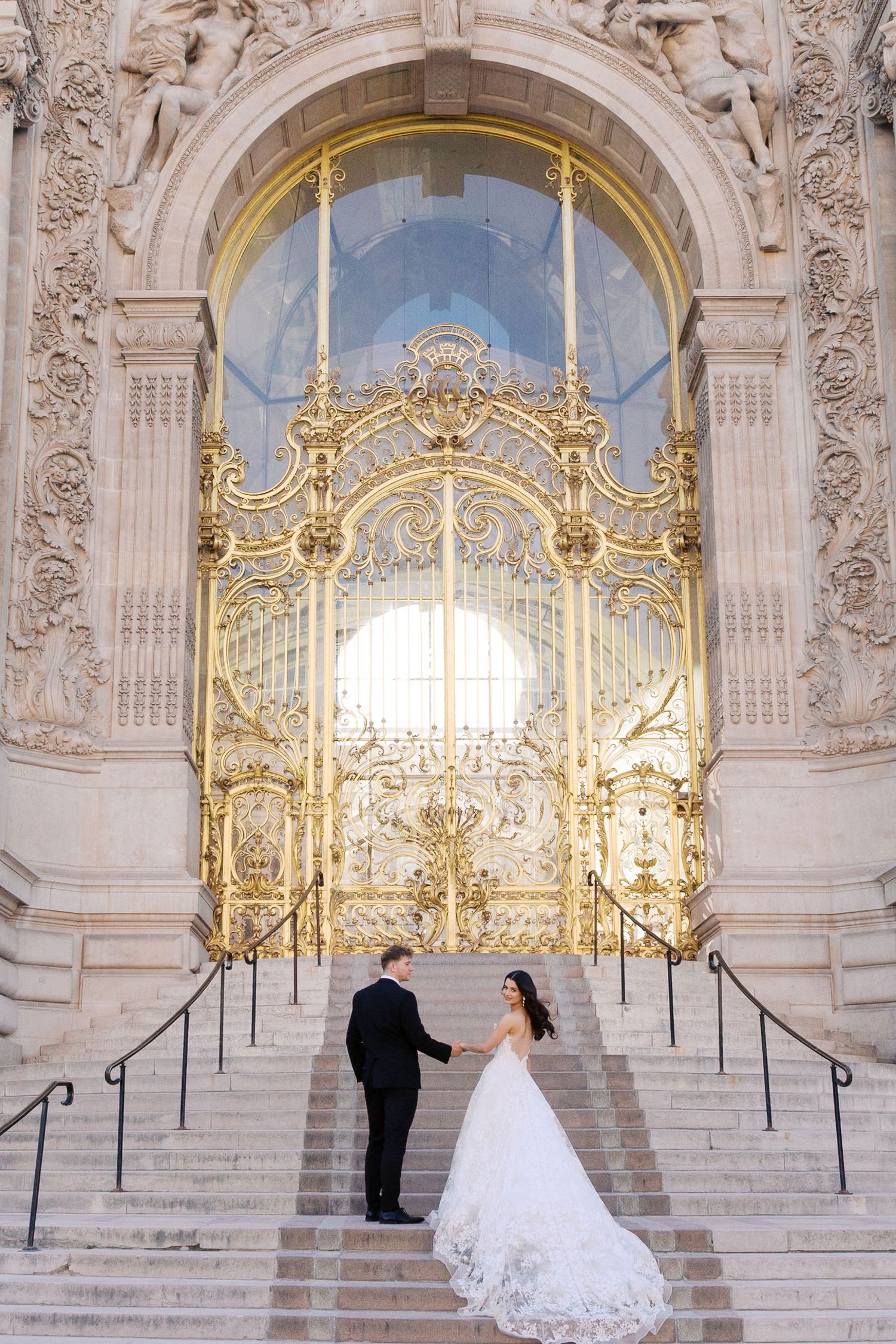 Elegant baroque palace interior with ornate gold details and grand staircase creates stunning architectural backdrop for wedding couple.