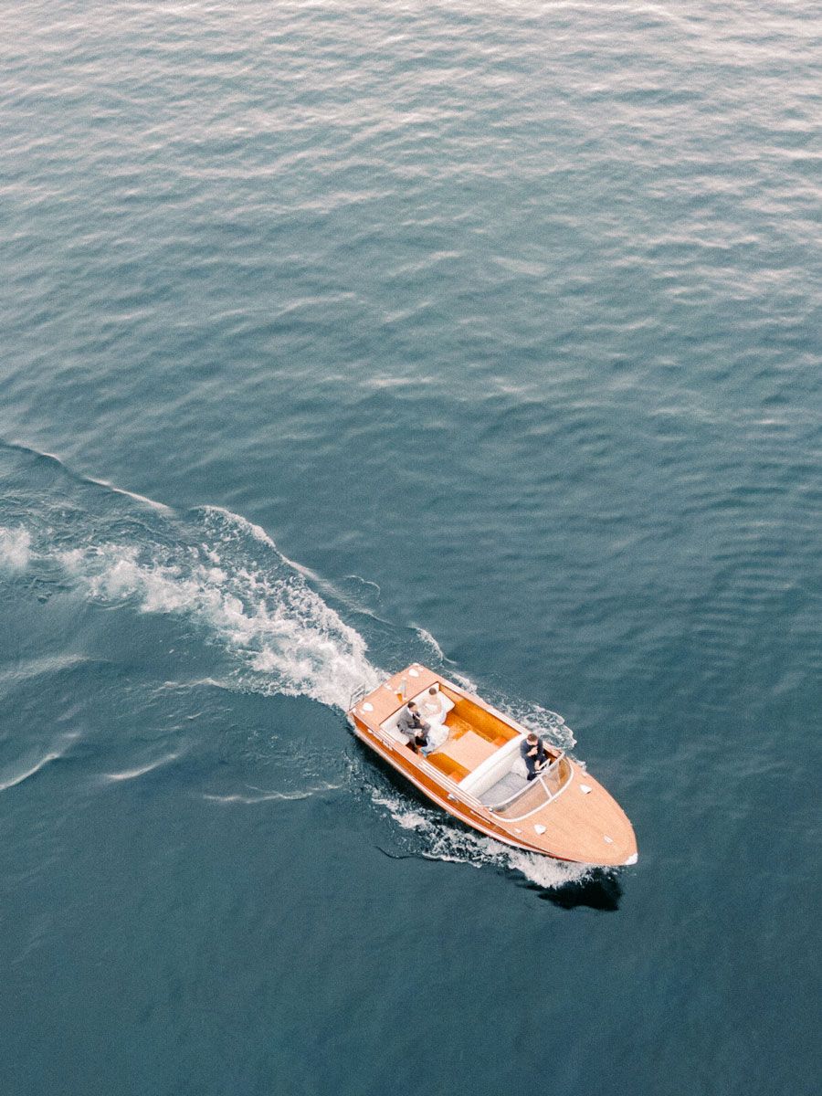 Aerial drone view of a luxury speedboat cruising through blue waters at Lake Garda with wedding couple.