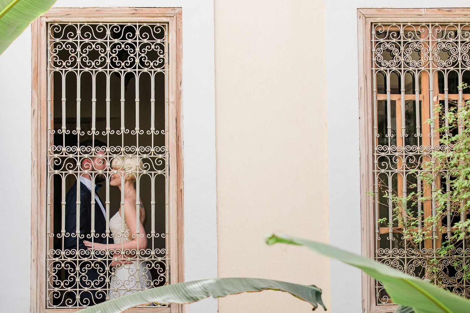Elegant white archways with decorative iron windows in Mediterranean courtyard.
