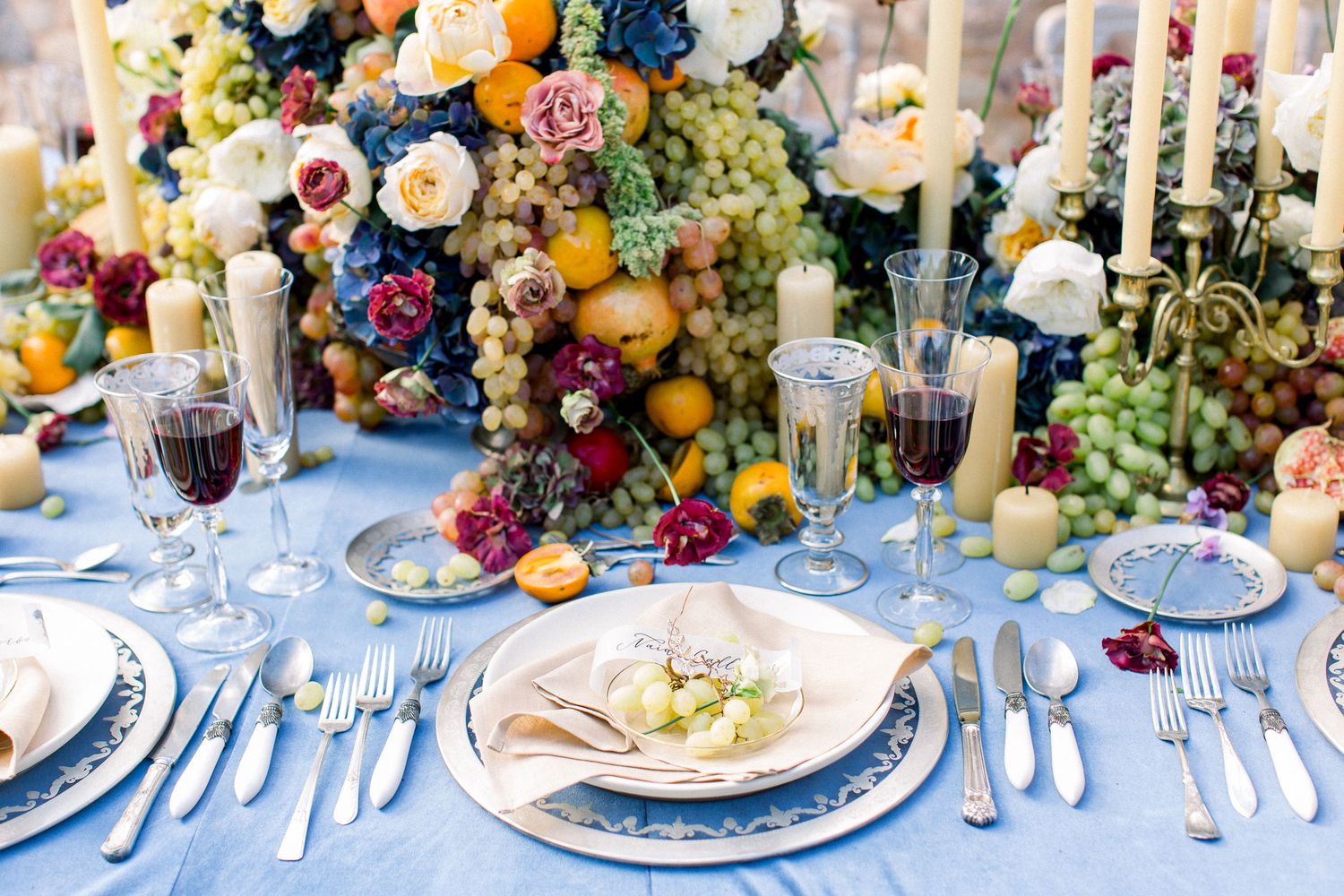 Elegant table settings with white candles and fresh fruit centerpieces create a wedding romantic dining atmosphere in Greece