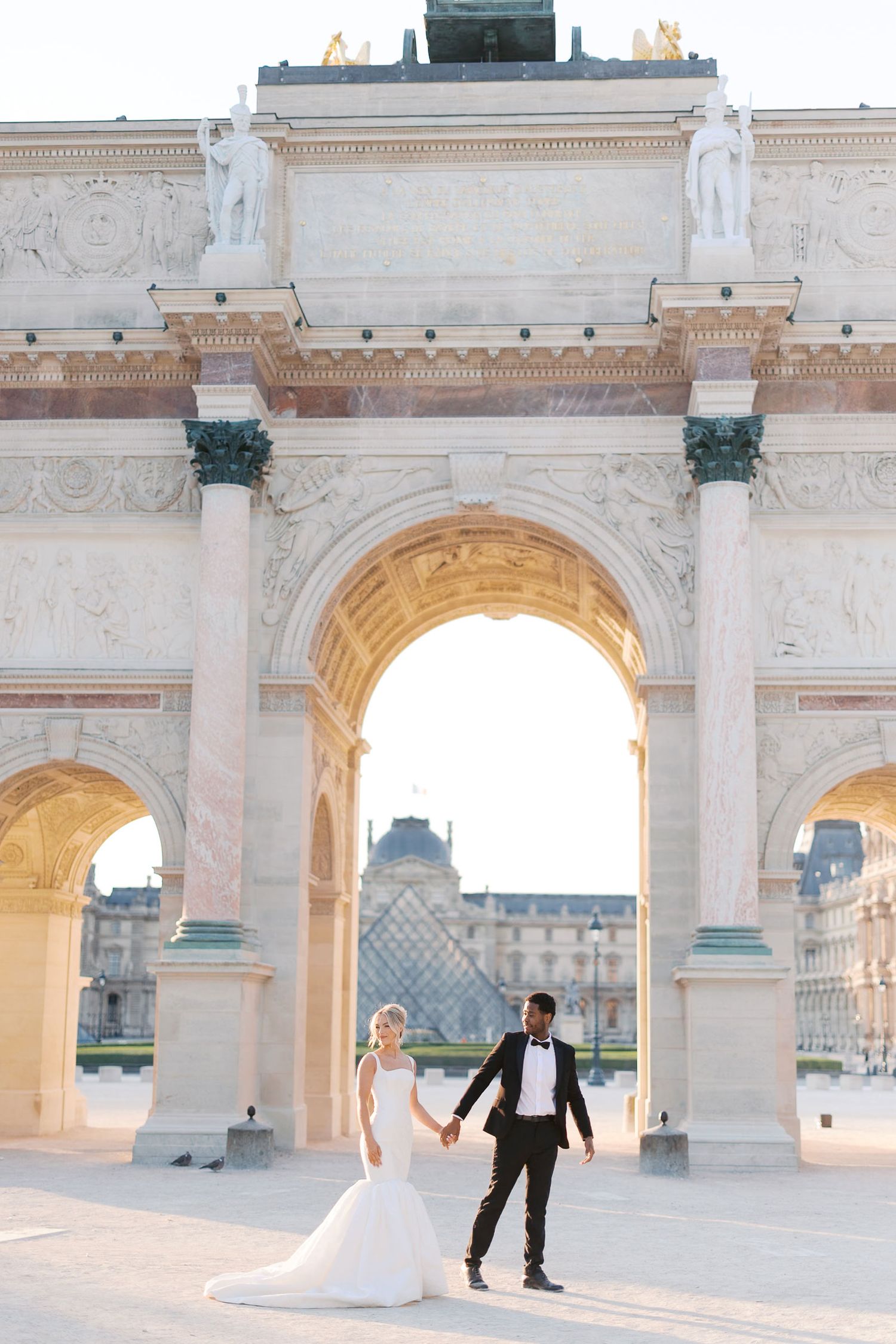 A romantic wedding photo session captured under elegant stone archways at the Louvre Museum in Paris.
