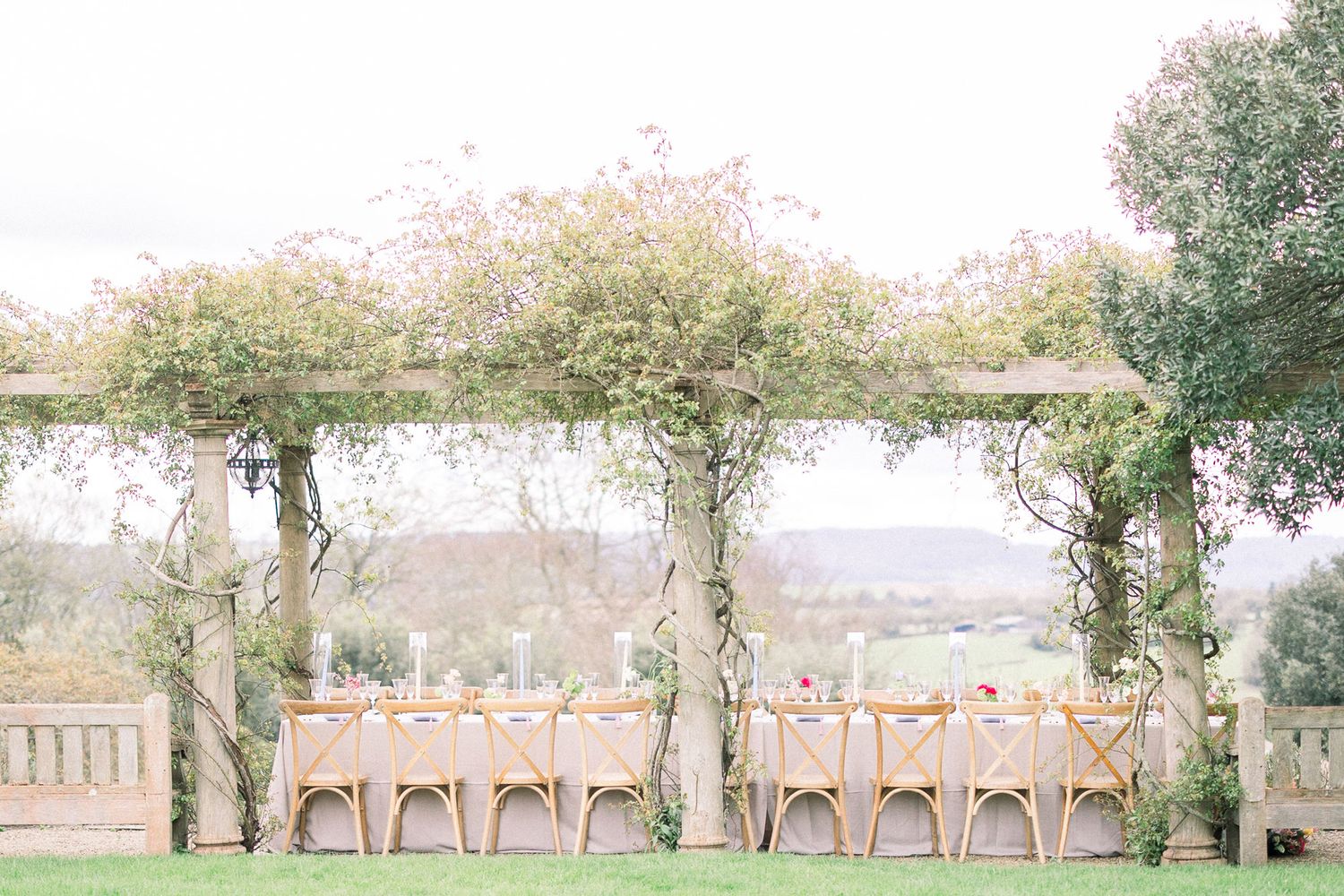 A rustic outdoor wedding ceremony setup with wooden chairs arranged in rows beneath tall trees in a natural setting at Euridge Manor.