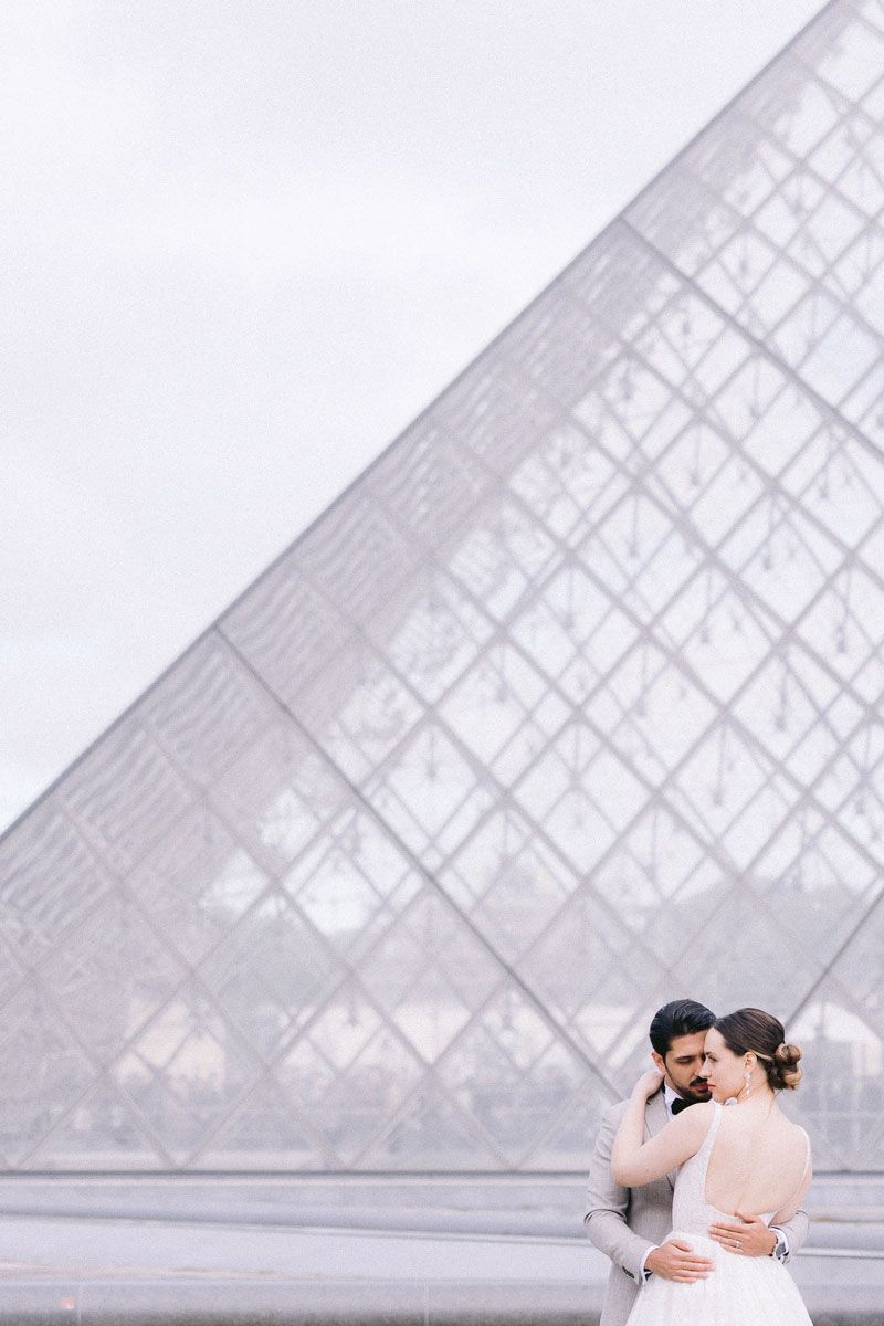 A romantic wedding photo session in front of the iconic Louvre pyramid in Paris.