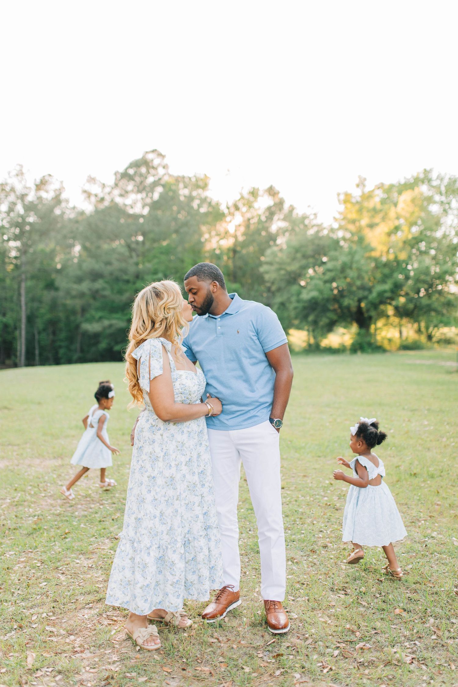 Family enjoying playful moments together in sunny outdoor field.
