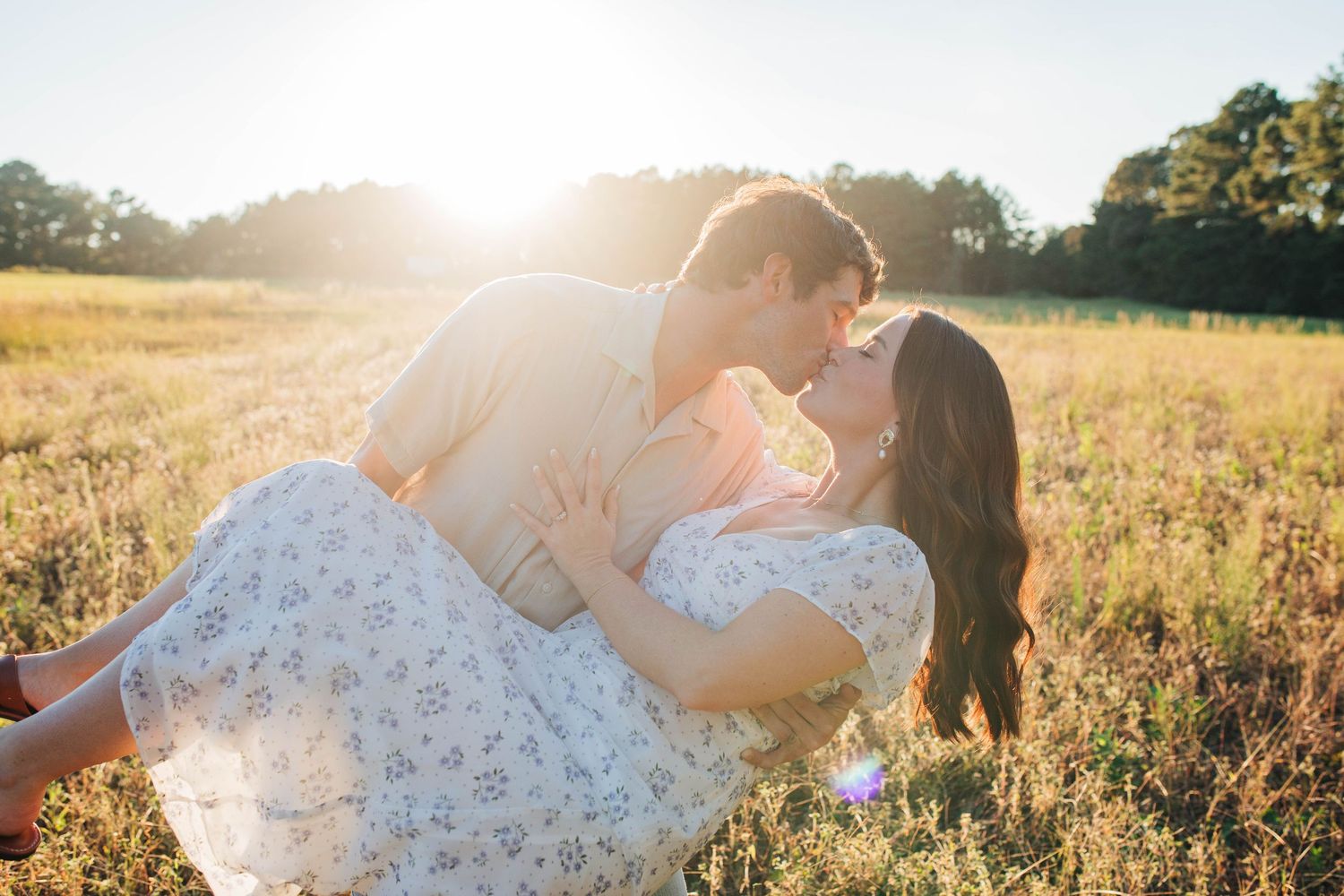 Silhouetted figures embrace in a sun-drenched field during sunset.