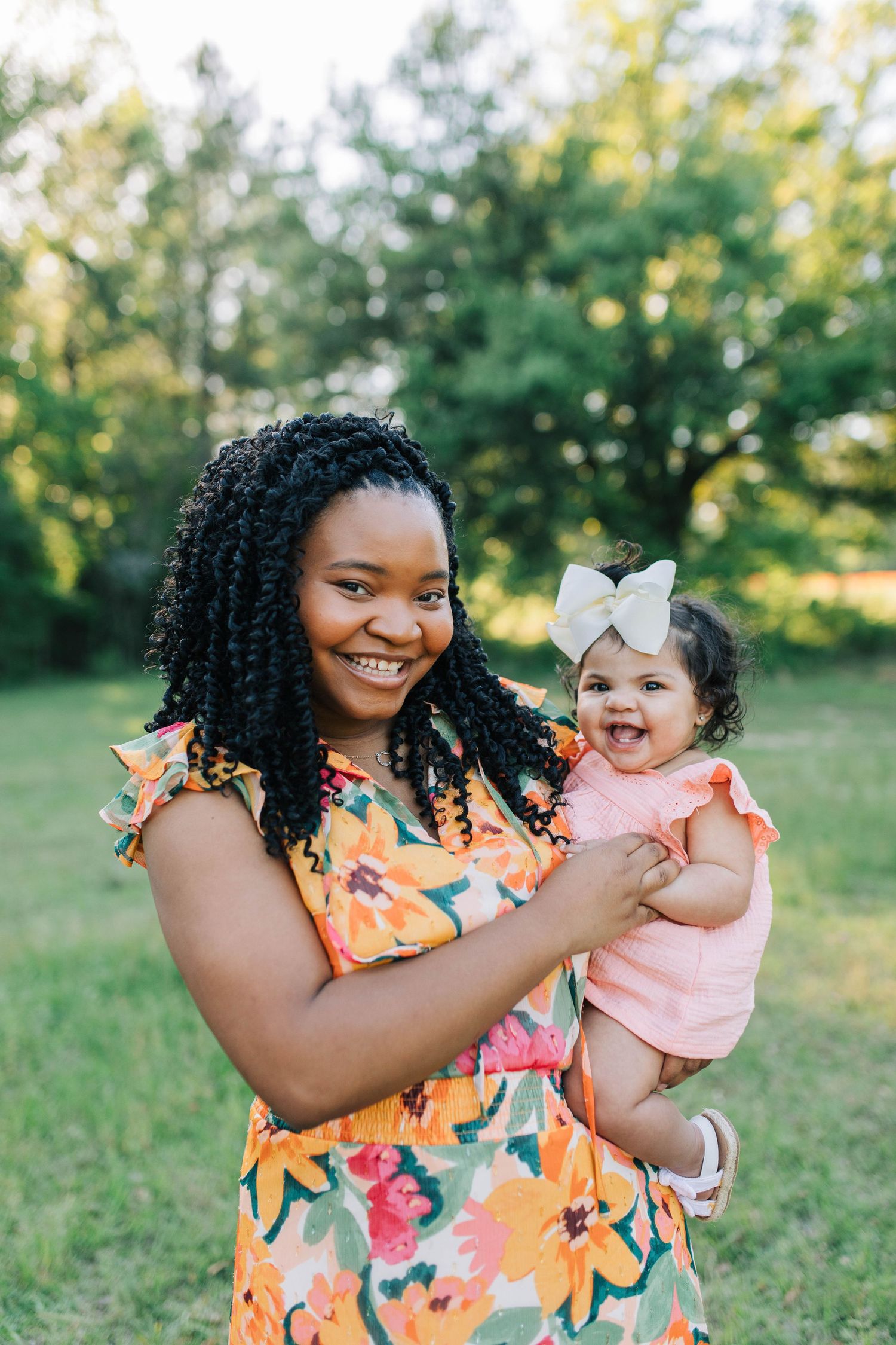 Parent and child in floral and coral outfits share playful moments outdoors.