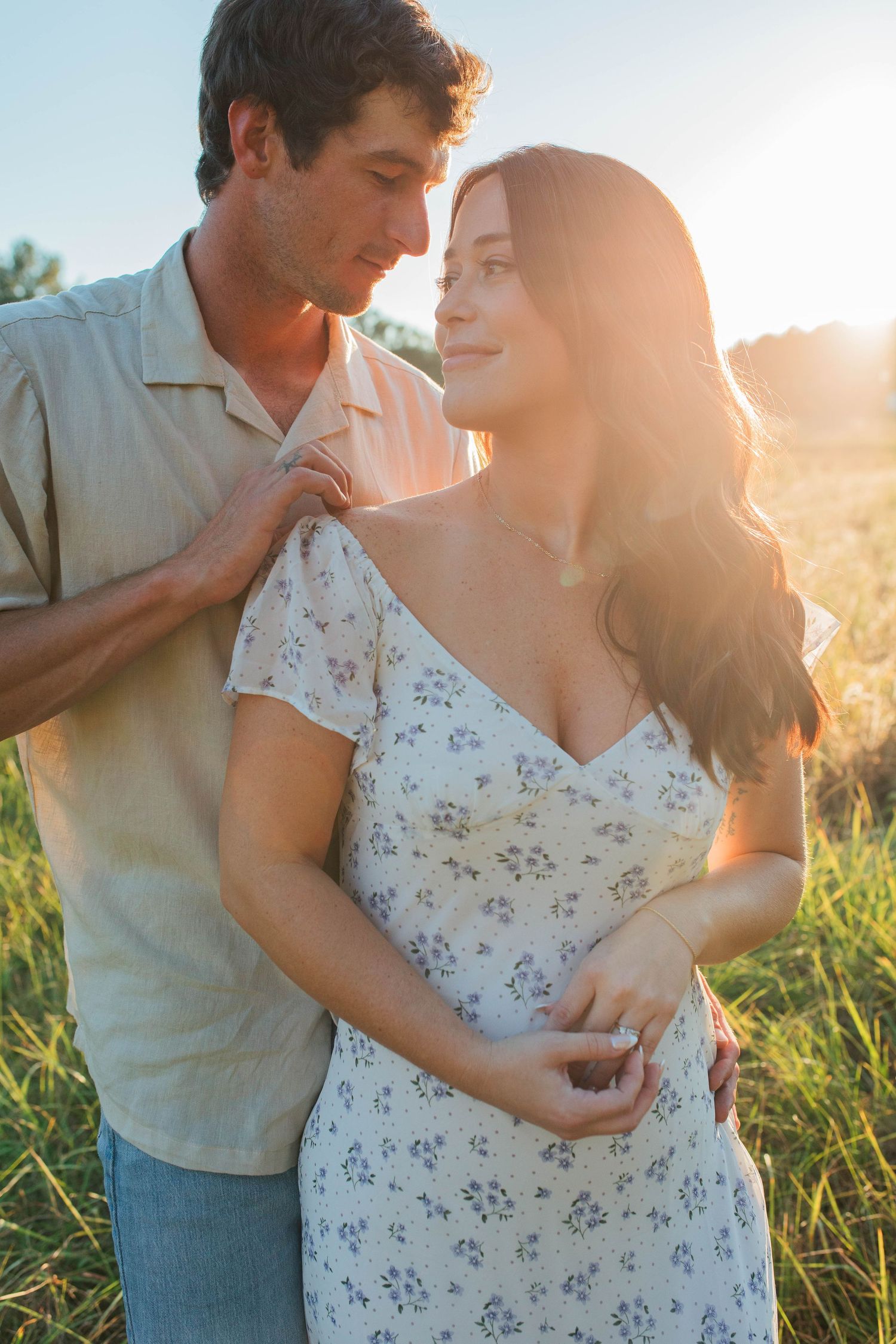 Intimate moment between couple in floral dress and casual wear during sunset.