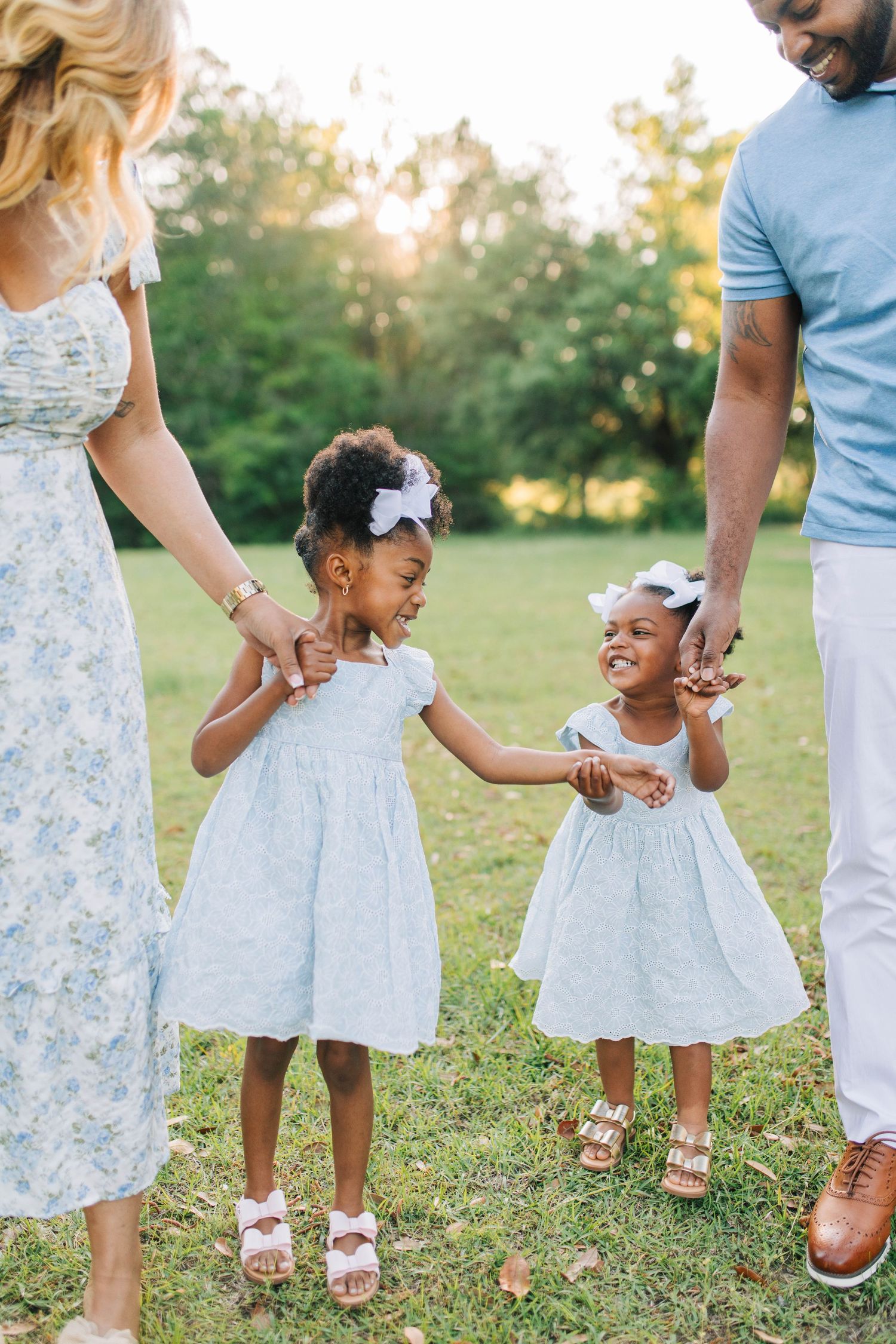 Family walking together in coordinated outfits on grass during golden hour.