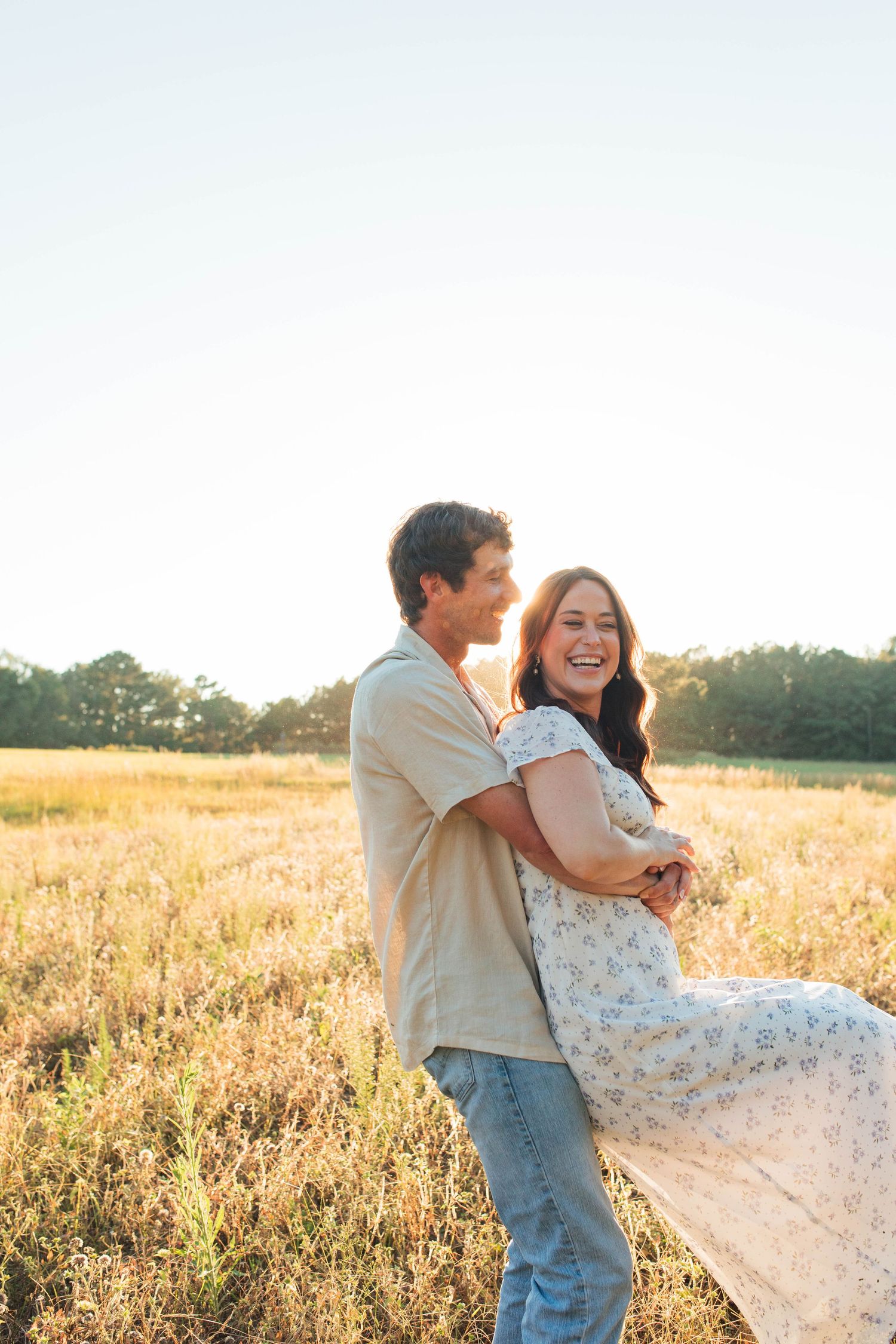 Dancing couple spins joyfully in a golden meadow at sunset.