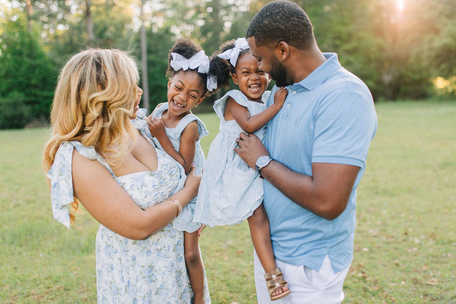 Family shares playful moments together in coordinated blue and white outfits outdoors.