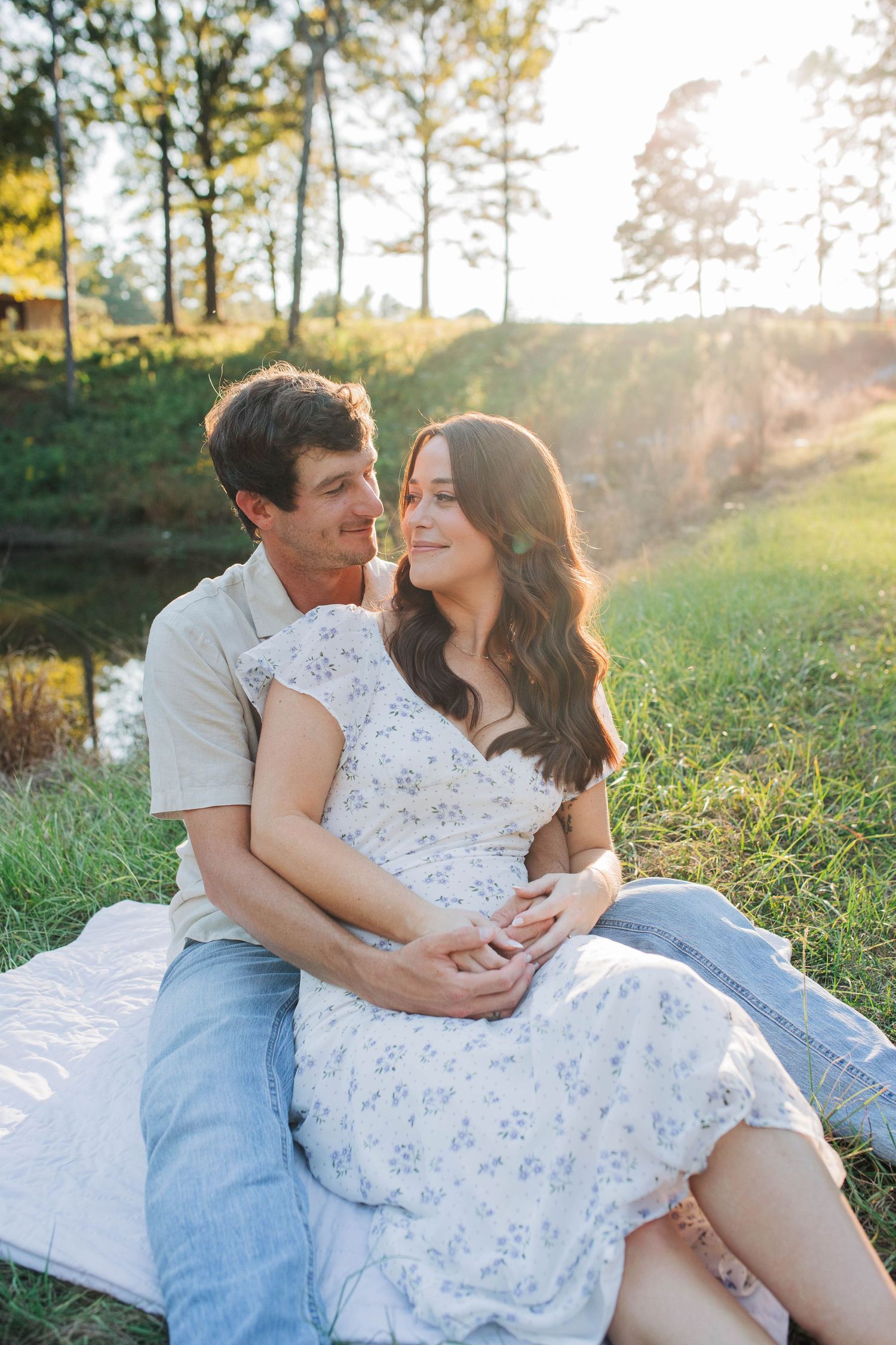 Couple sharing intimate moment on blanket in sunlit field.