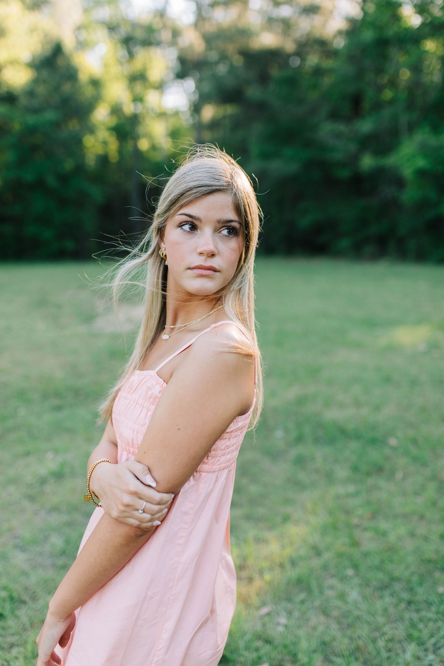 Woman in pink dress posing outdoors during golden hour portrait session.