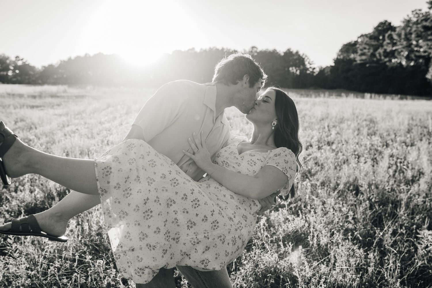 Romantic couple lying in a sunlit meadow during golden hour.
