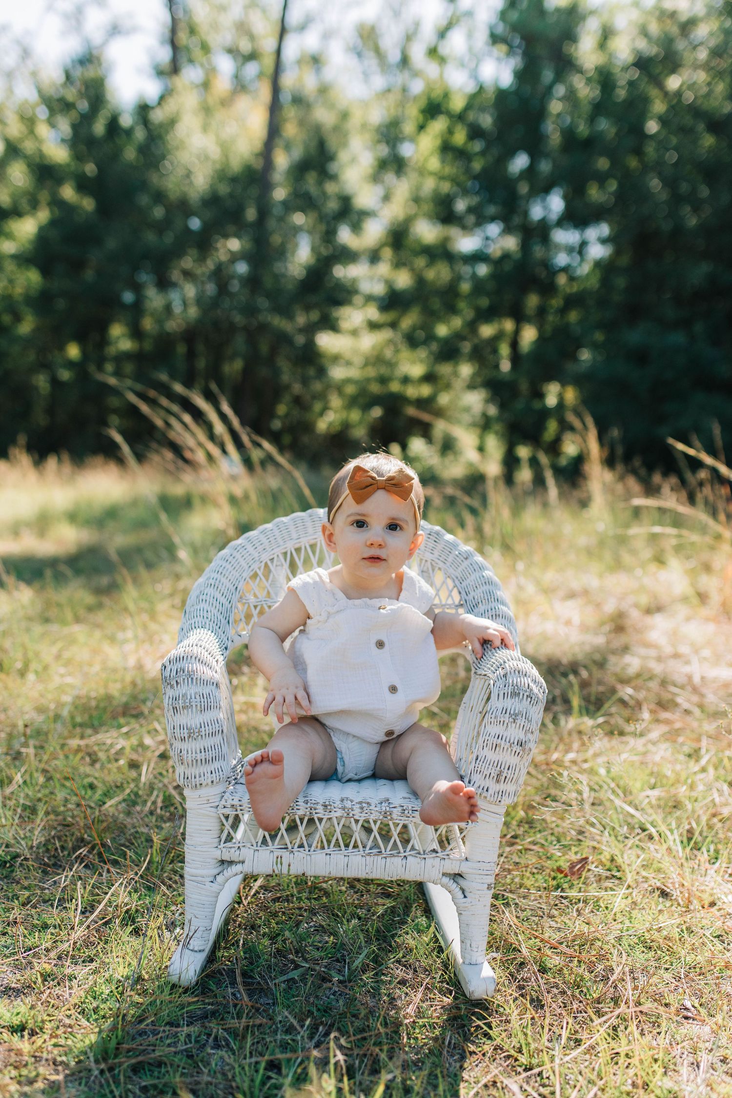 baby in a rocking chair. natural light. outside in a grassy field.