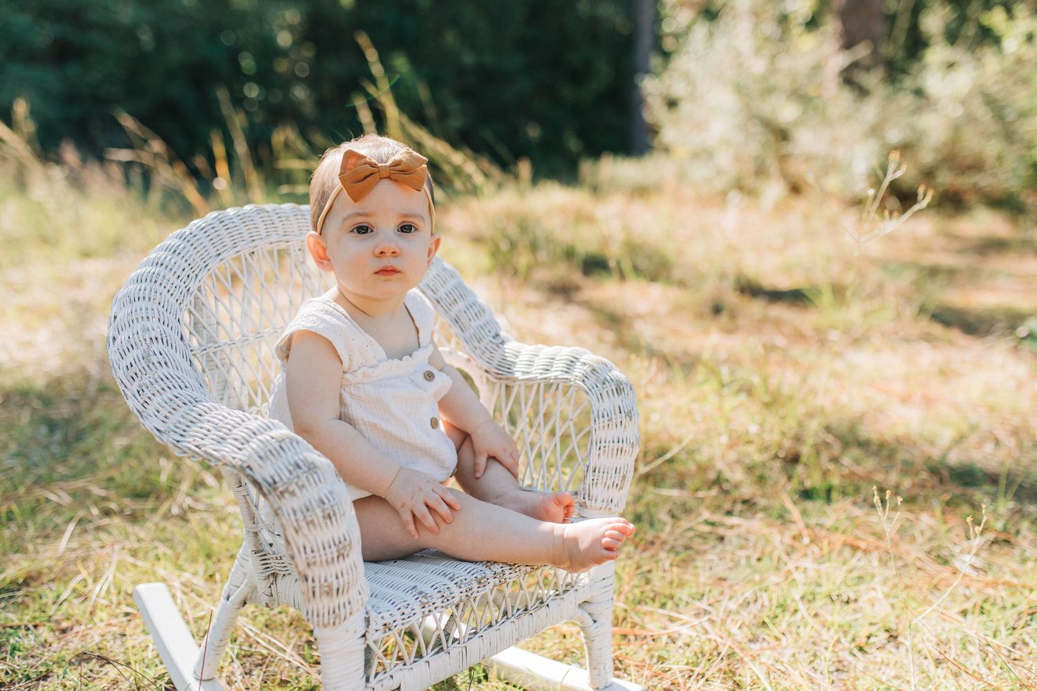 baby in a rocking chair. natural light. outside in a grassy field.