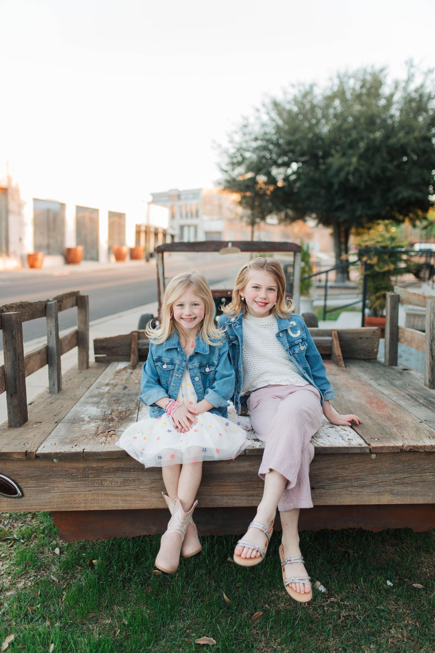 Two children sitting and laughing together on wooden deck with city backdrop.