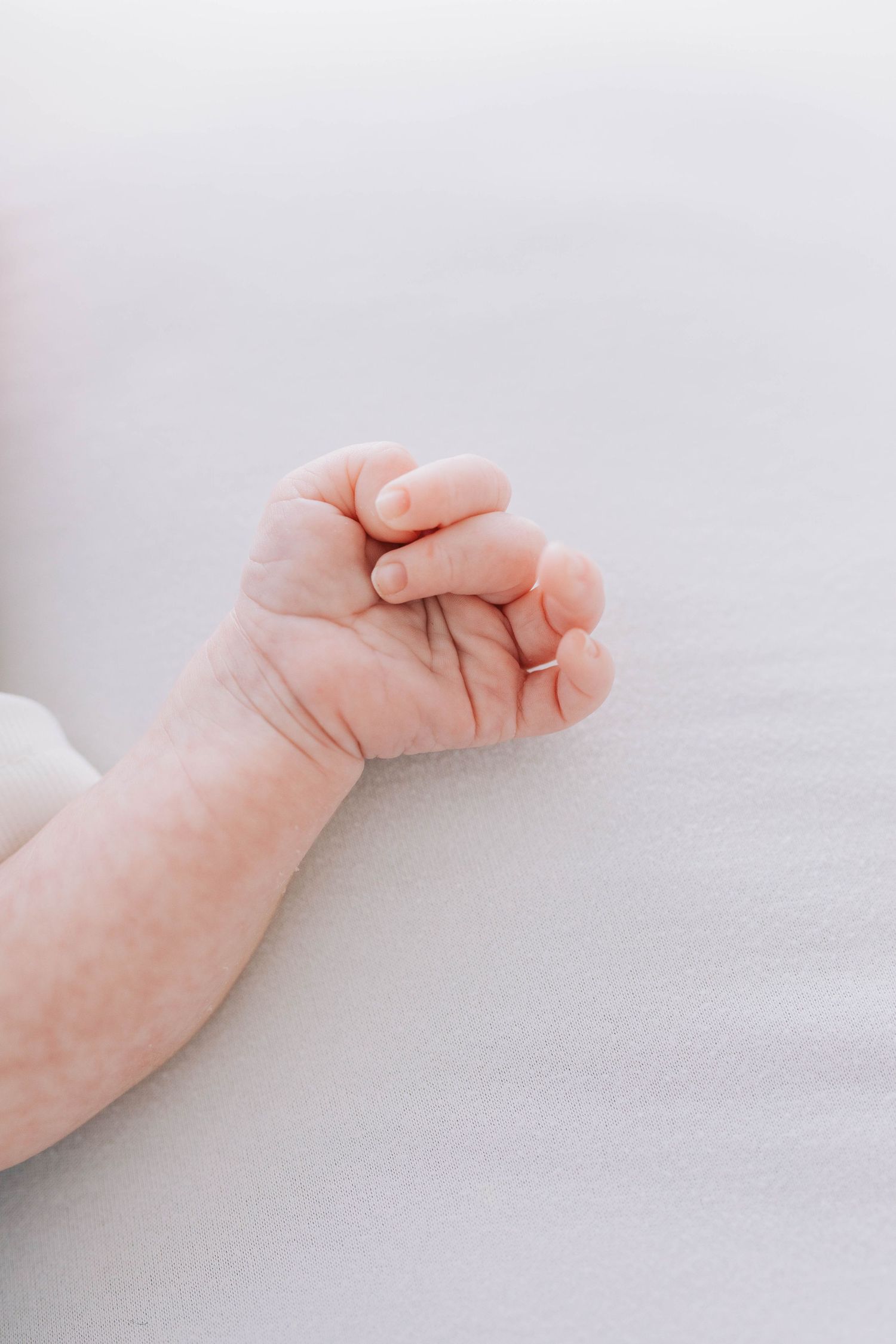 Close-up of tiny newborn baby fist against white background.