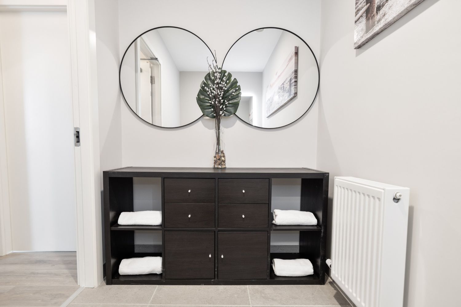 Modern hallway with twin round mirrors, dark console unit, and simple decorative styling in a Dublin interior