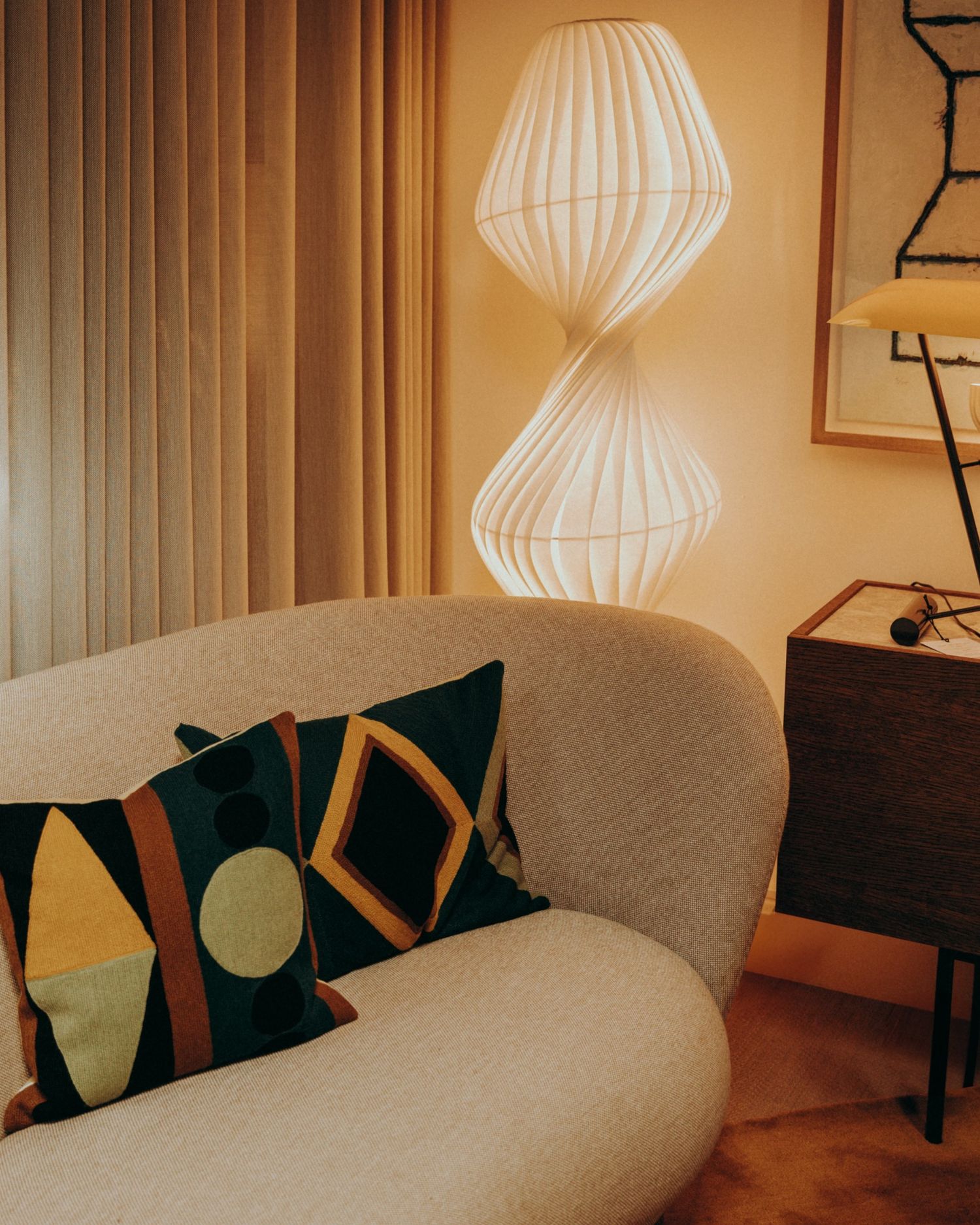 Curved sofa with graphic pillows and sculptural floor lamp — cosy interior styled and photographed by Sigi in Dublin.