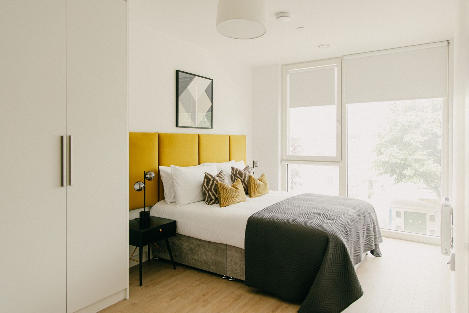 Sunlit bedroom featuring a bold yellow headboard, warm tones, and clean styling, photographed in Dublin interior.