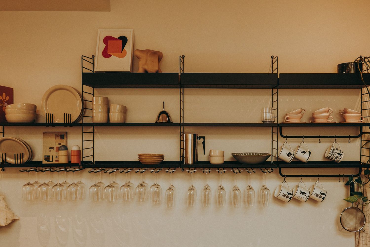 Minimalist open shelving kitchen featuring ceramic dishware, wine glasses, and playful art — styled with simplicity and charm in Dublin