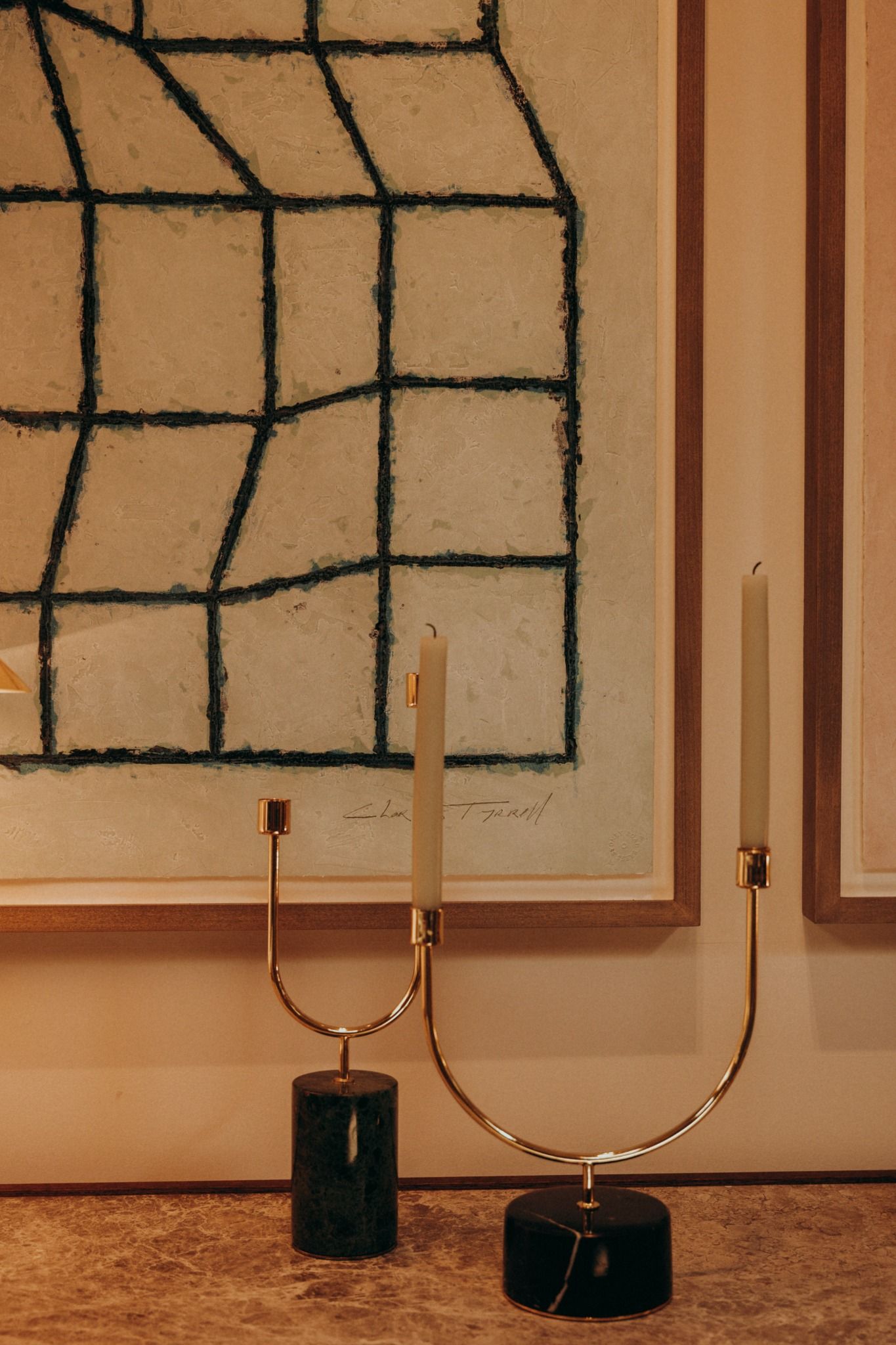 Elegant gold candlesticks on a marble surface set against modern sculptural wall art, styled in warm natural light, by Sigi Photos Dublin