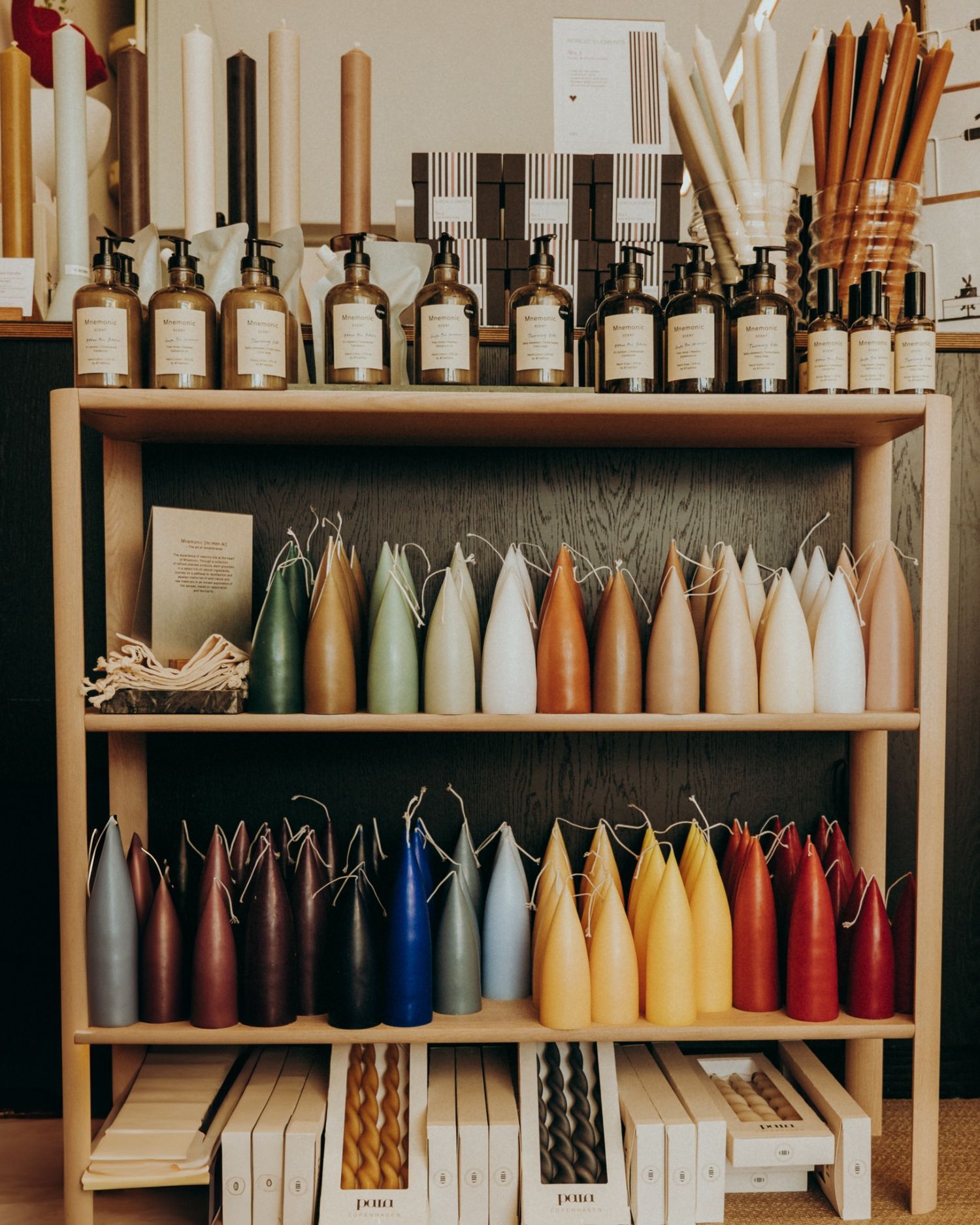 Taper candles and organic scents arranged on wooden shelves — shop styling photographed in Dublin by Sigi.