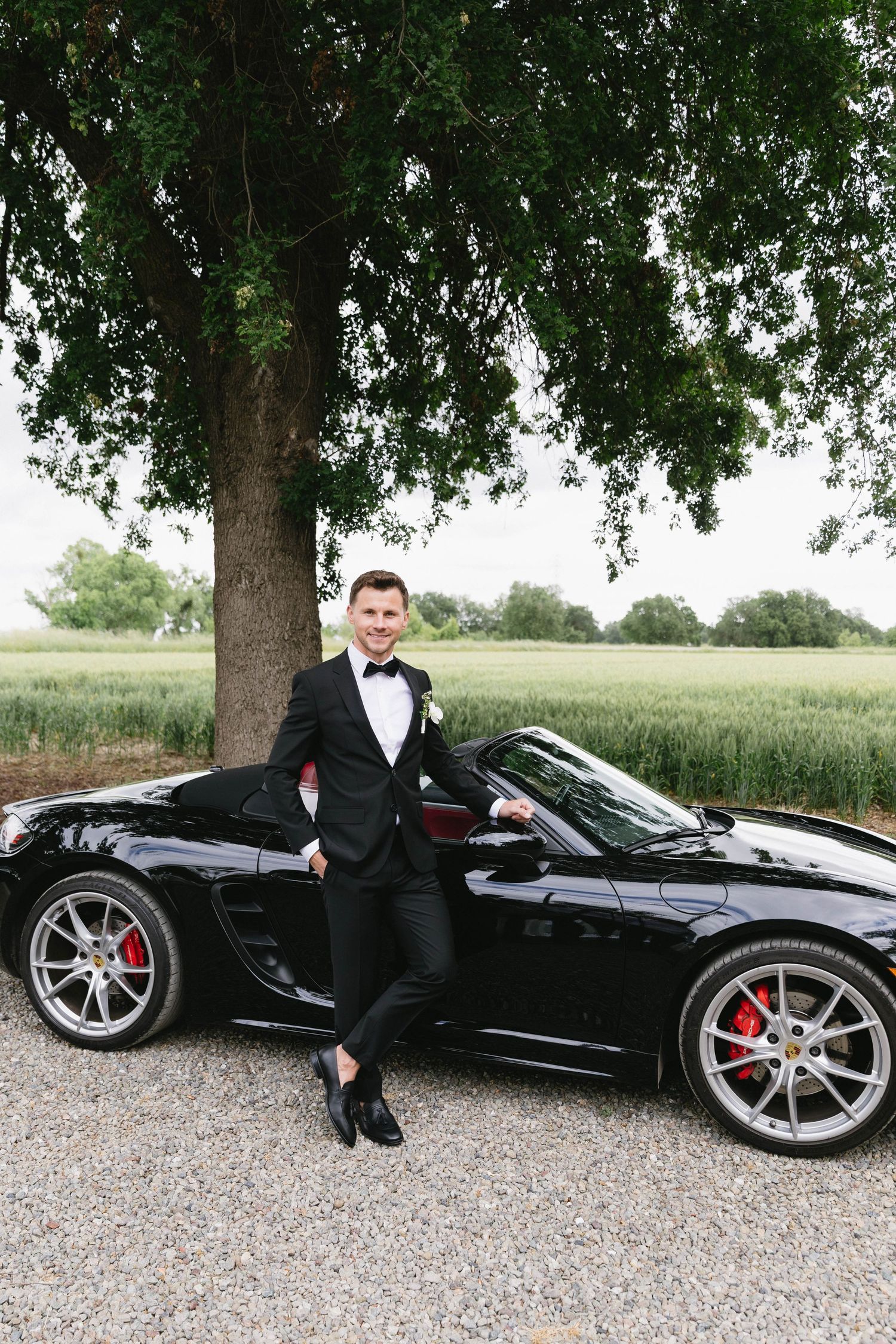 Wedding party photos featuring luxury sports car and formal attire under tree canopy.