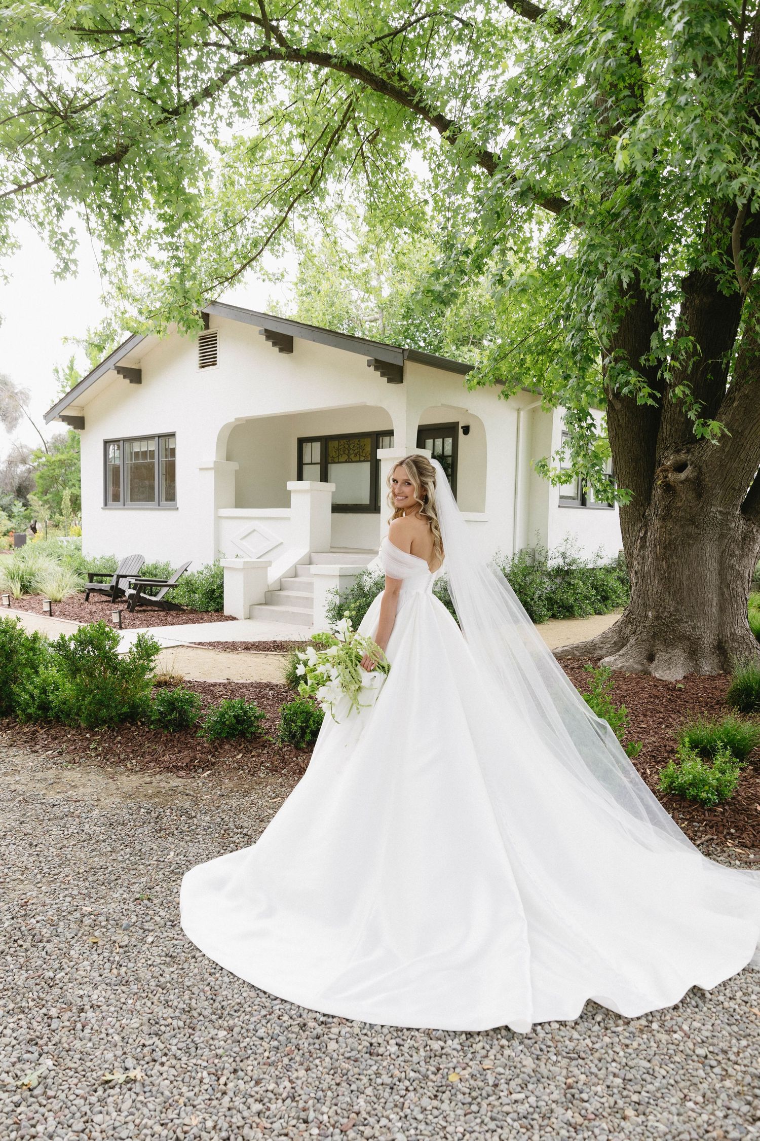 A flowing white wedding dress photographed in a series against a rustic outdoor backdrop.
