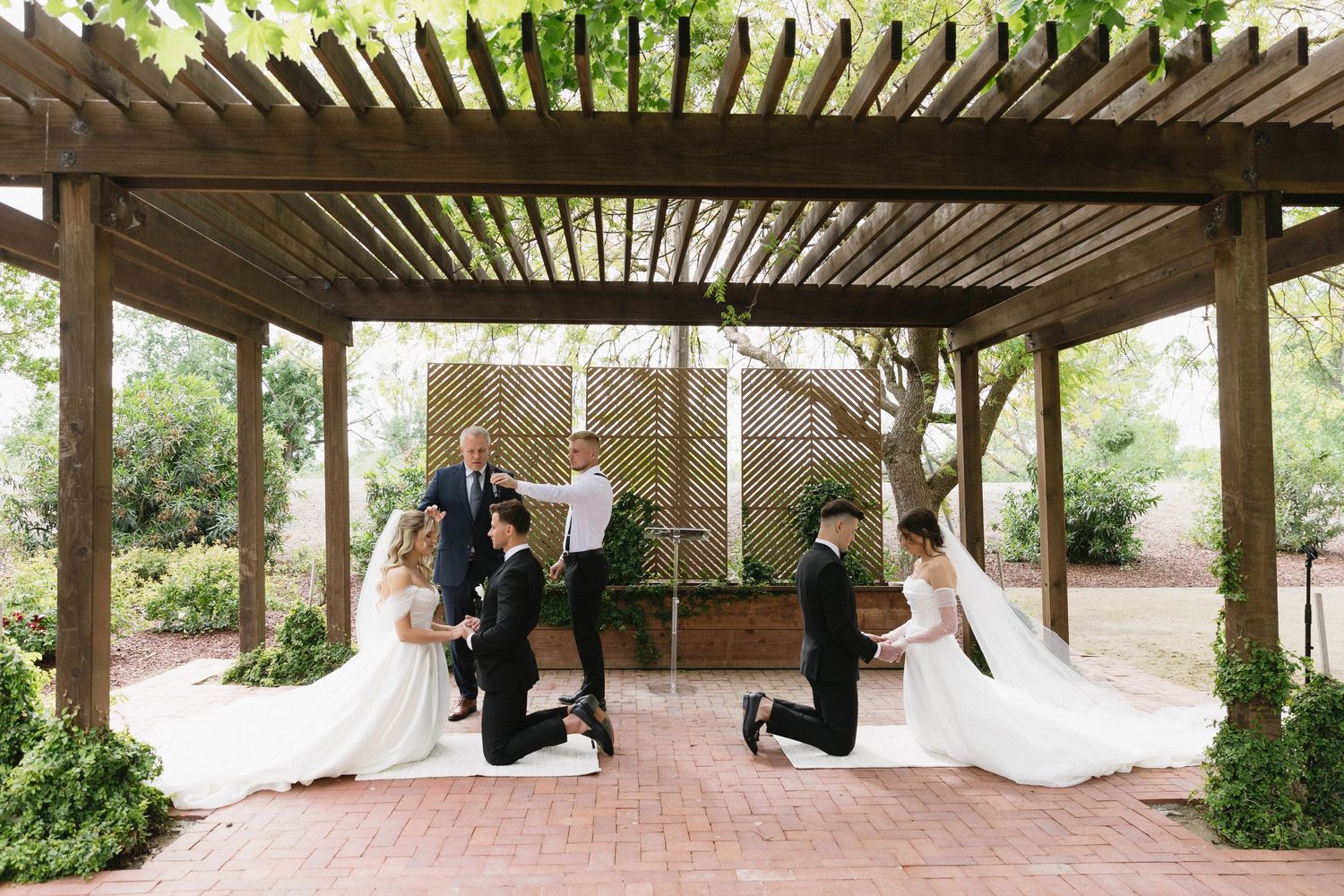 Wide angle view of a wooden pergola wedding venue with natural garden surroundings.