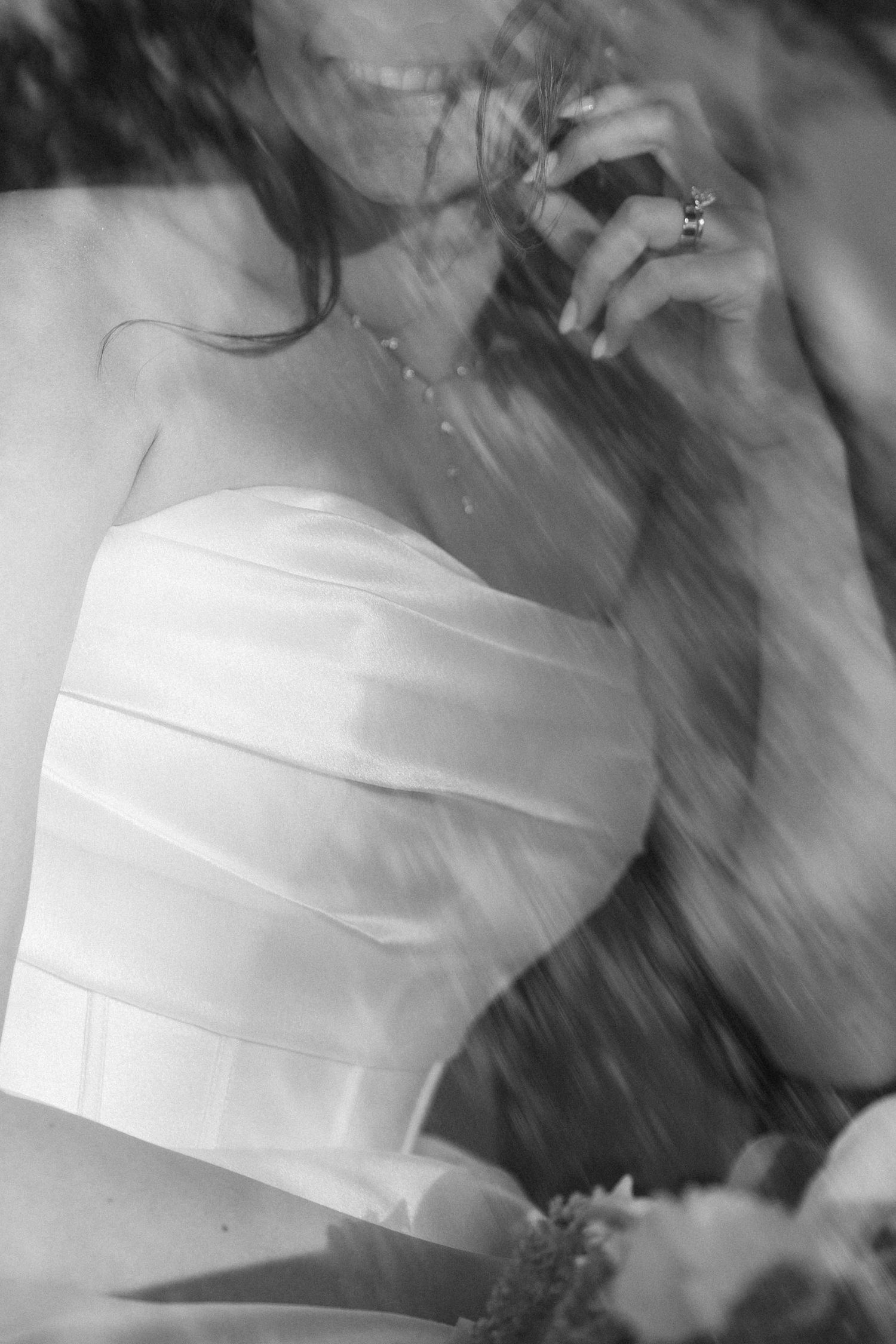 Black and white artistic photo of a bride in a strapless wedding dress with delicate details.