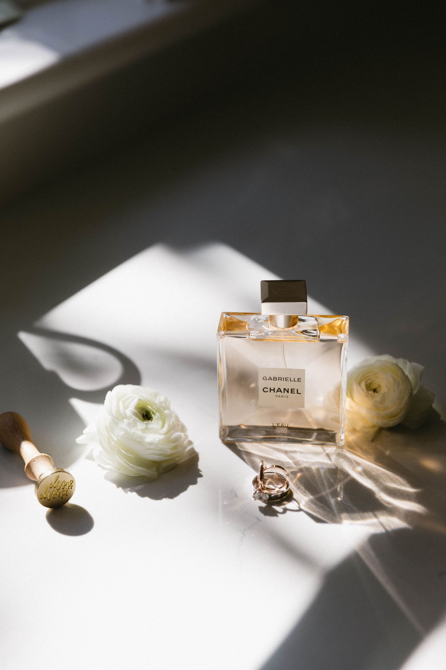 Perfume bottle and white flowers arranged in dramatic lighting.