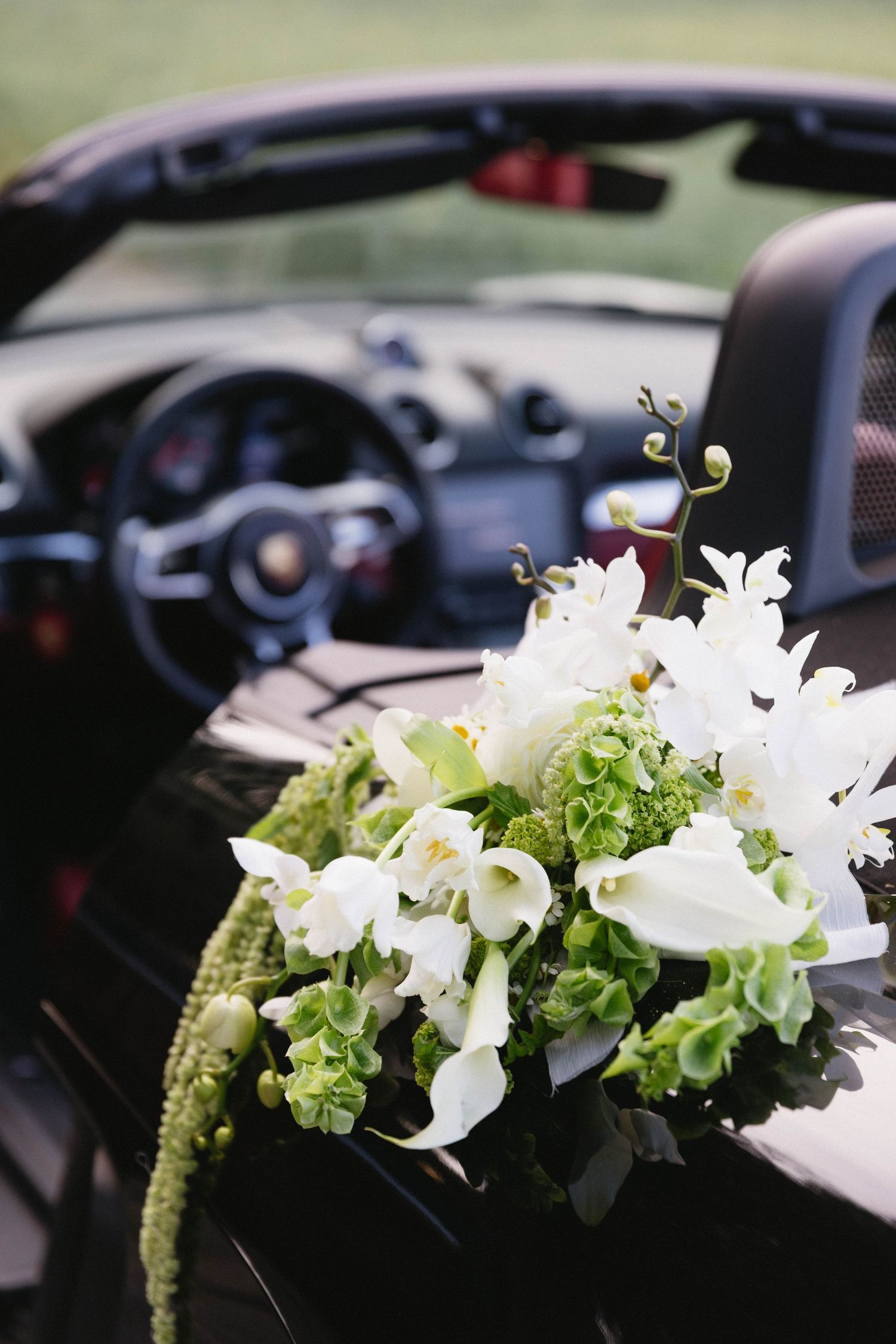 White floral arrangement with lilies decorating the dashboard of a luxury car.
