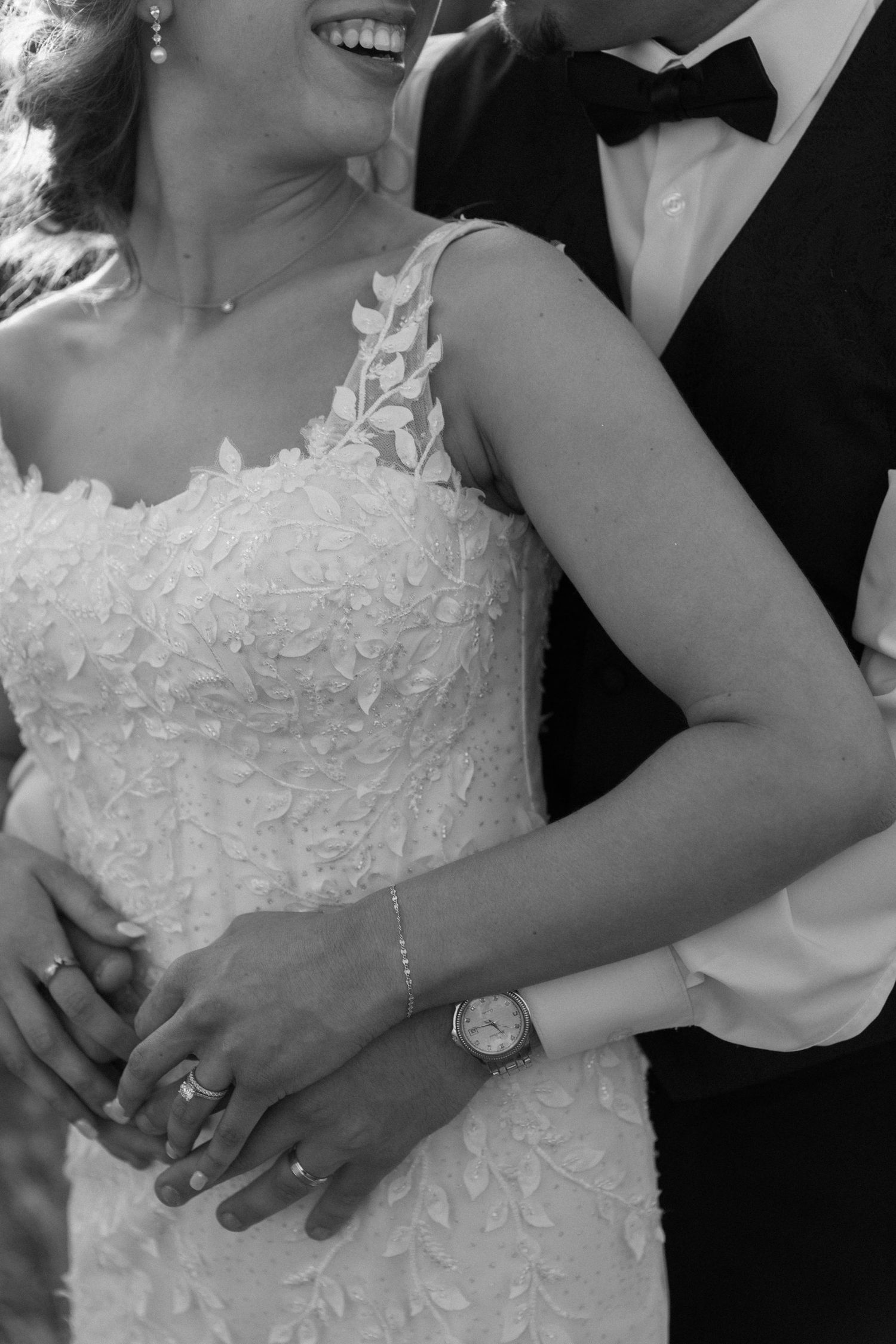 Close-up details of a white lace wedding dress and formal attire in black and white.