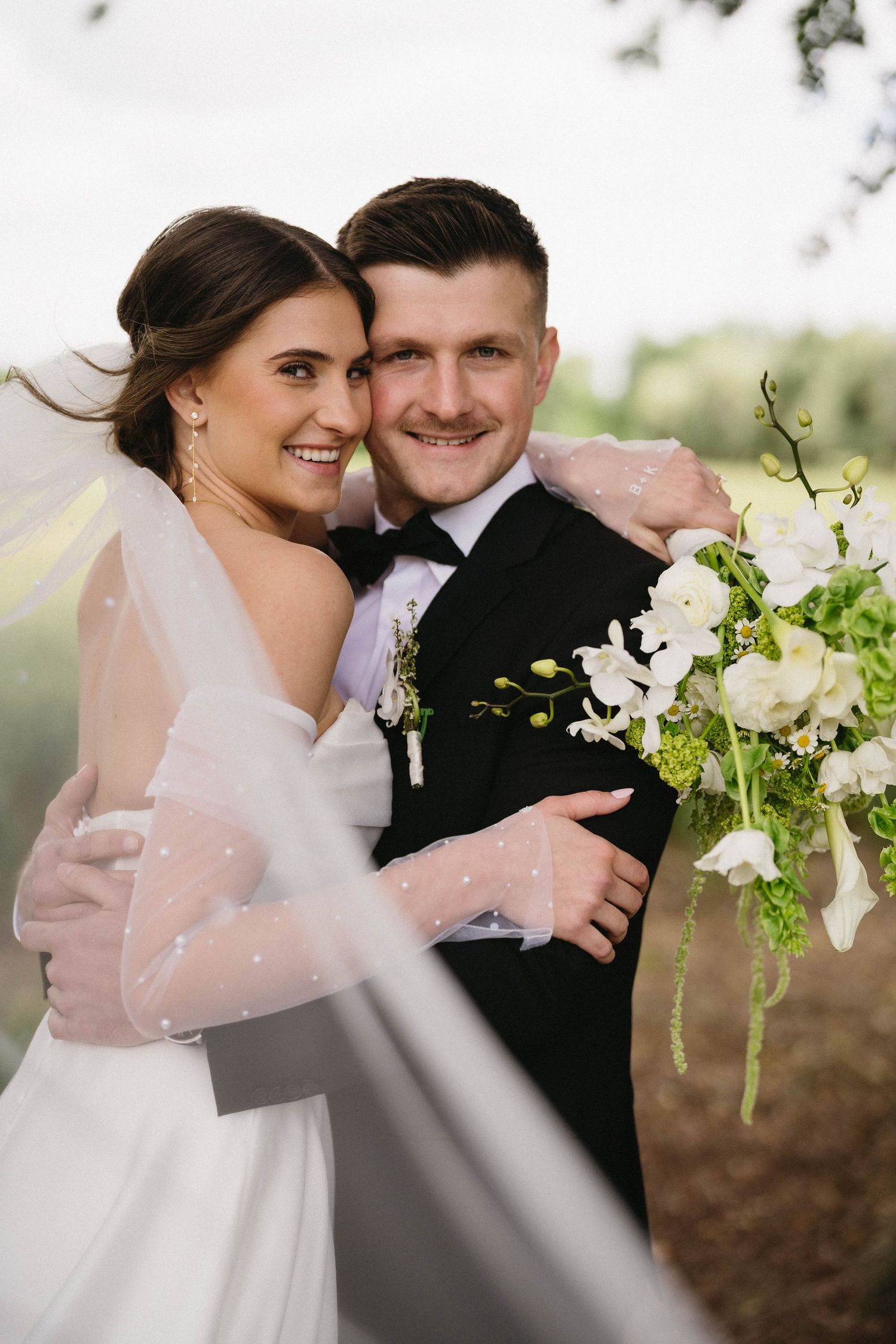 Joyful wedding portraits featuring white and green floral arrangements in natural lighting.