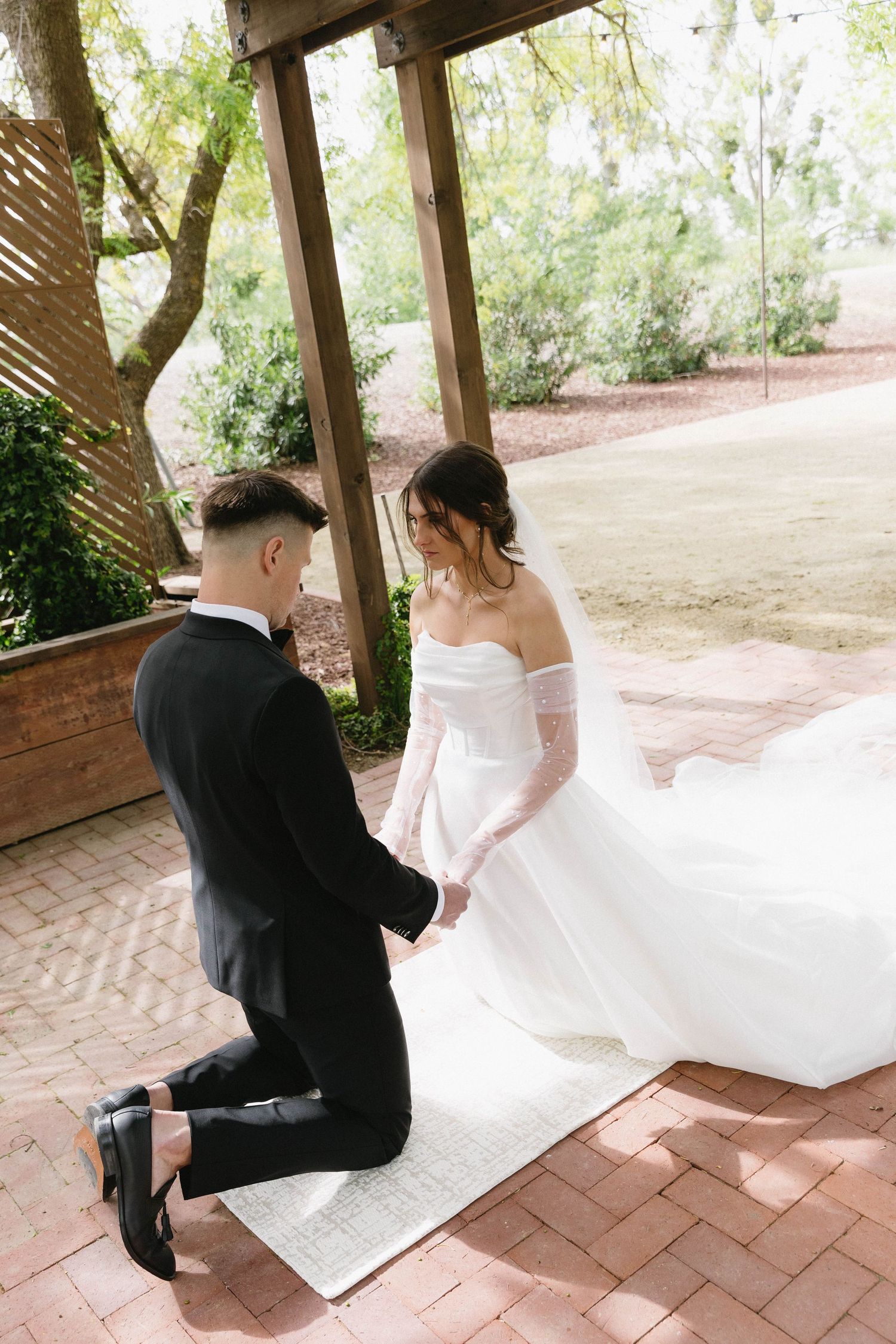 Wedding couple interacting during their first look on a brick patio under a wooden structure.