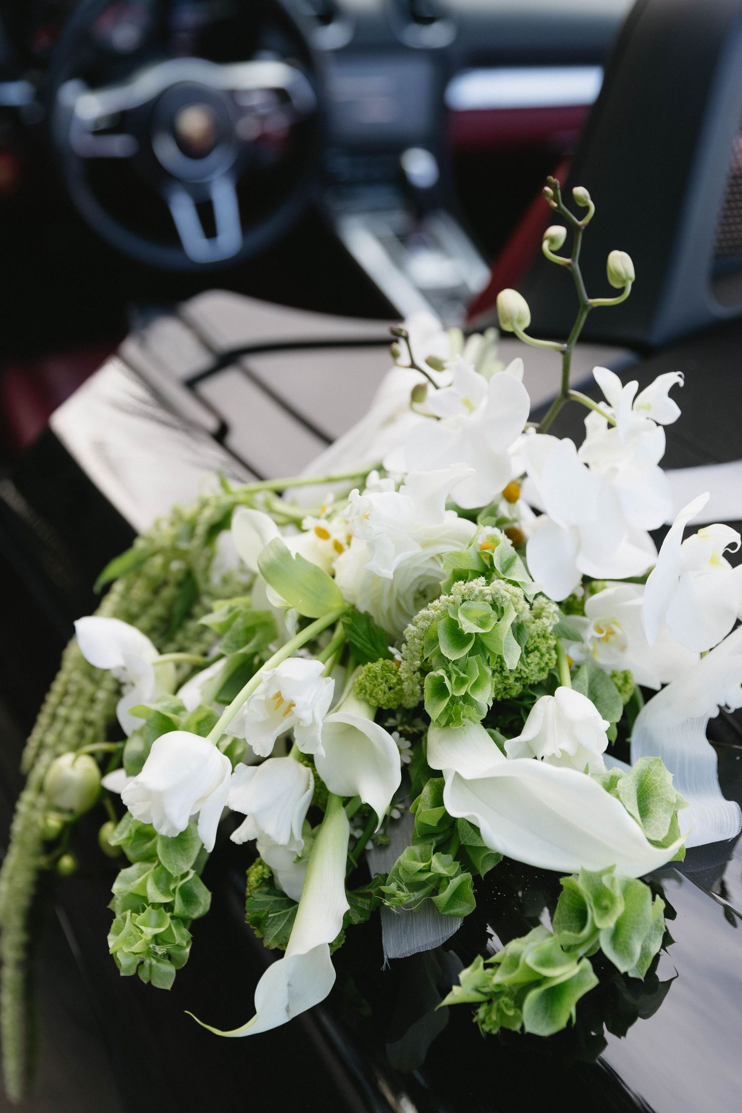 White and green floral arrangement displayed in a car interior.